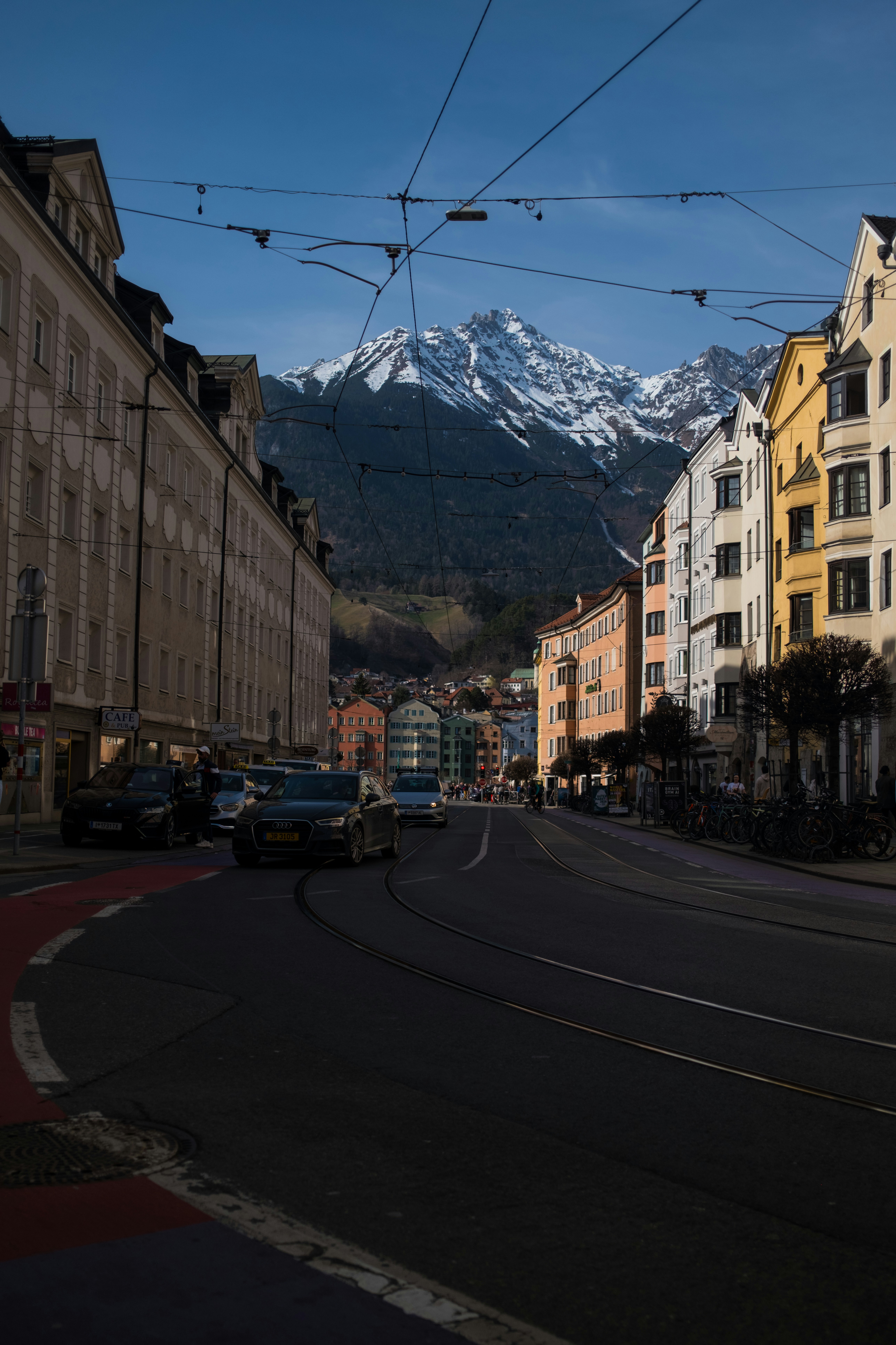 Street view with colorful buildings and snowy mountains.
