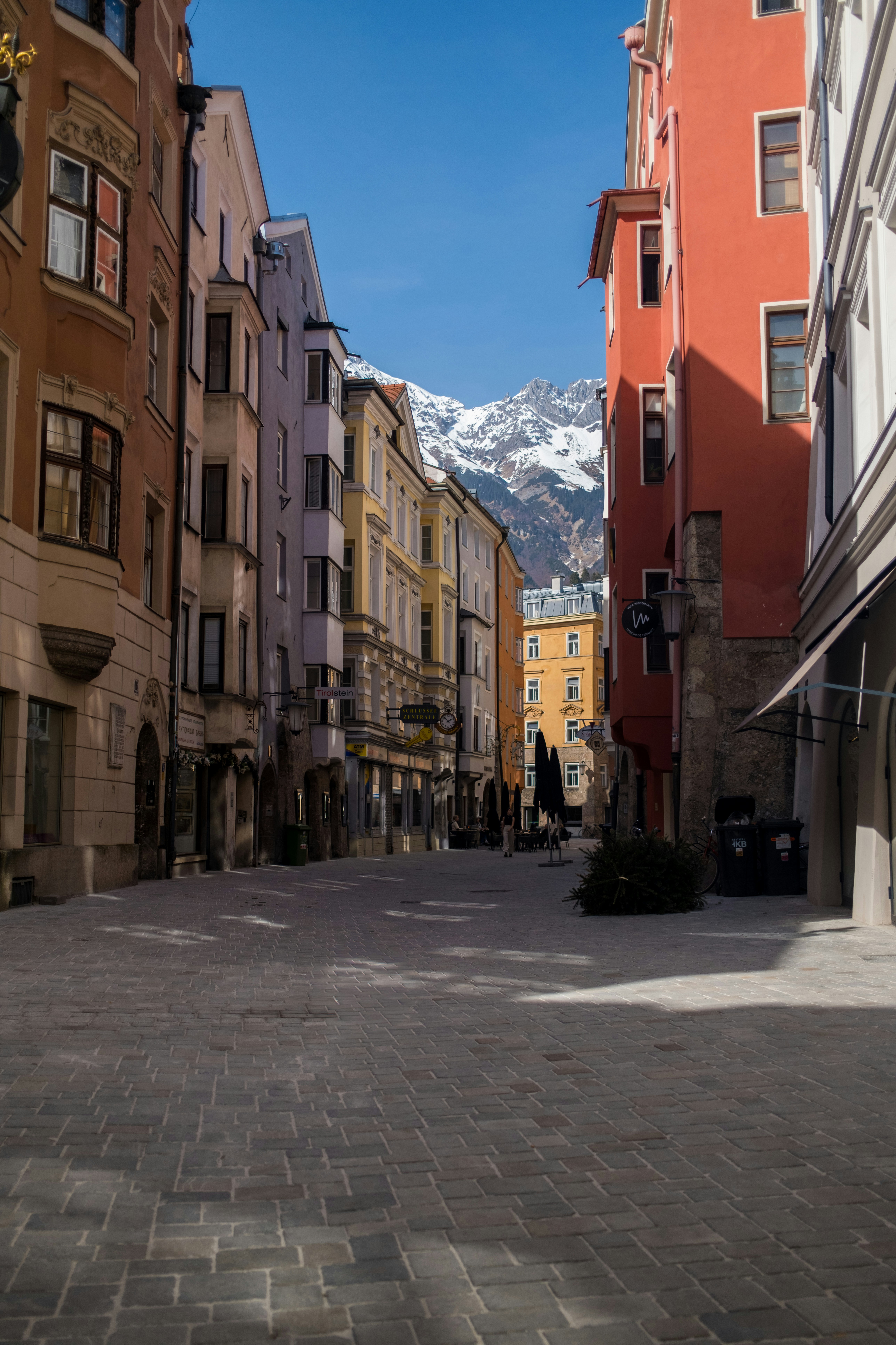 Colorful buildings line a cobblestone street with mountains beyond.