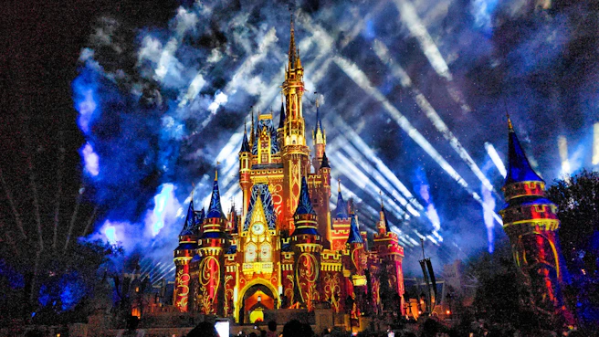 Disney World castle illuminated with colorful lights and projections at night