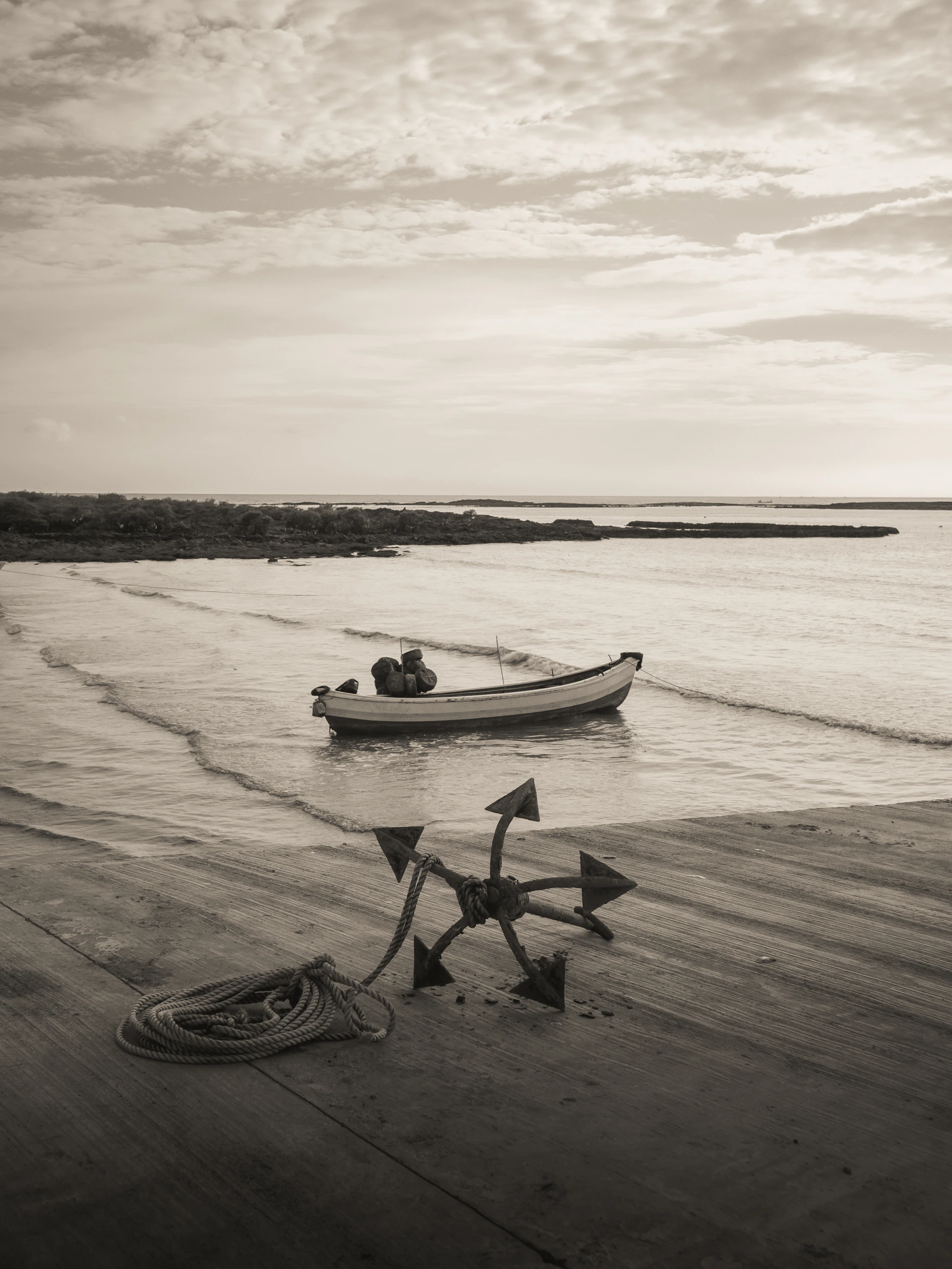 Boat and anchor on a wooden pier by the sea