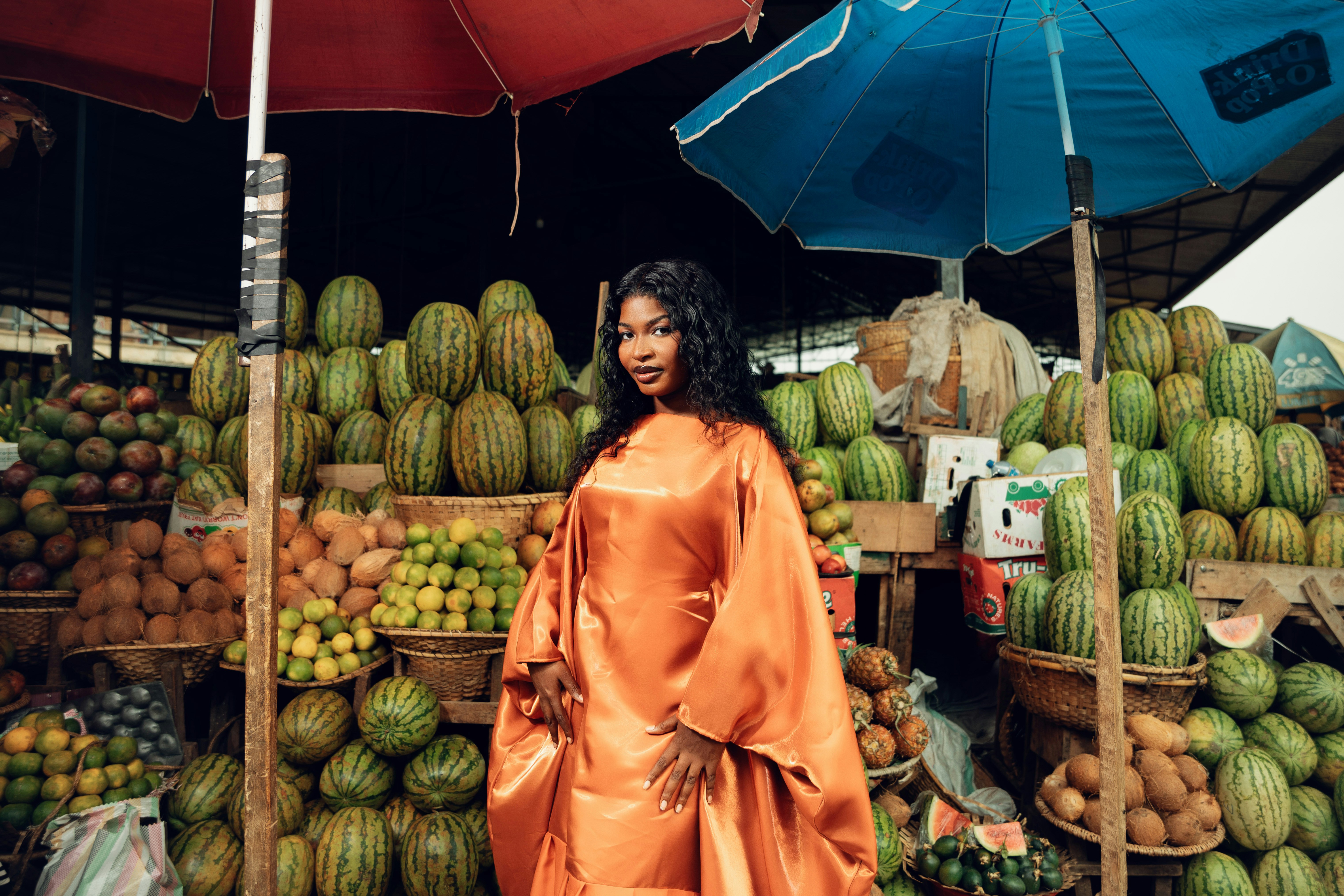 Woman in orange dress at a fruit stand