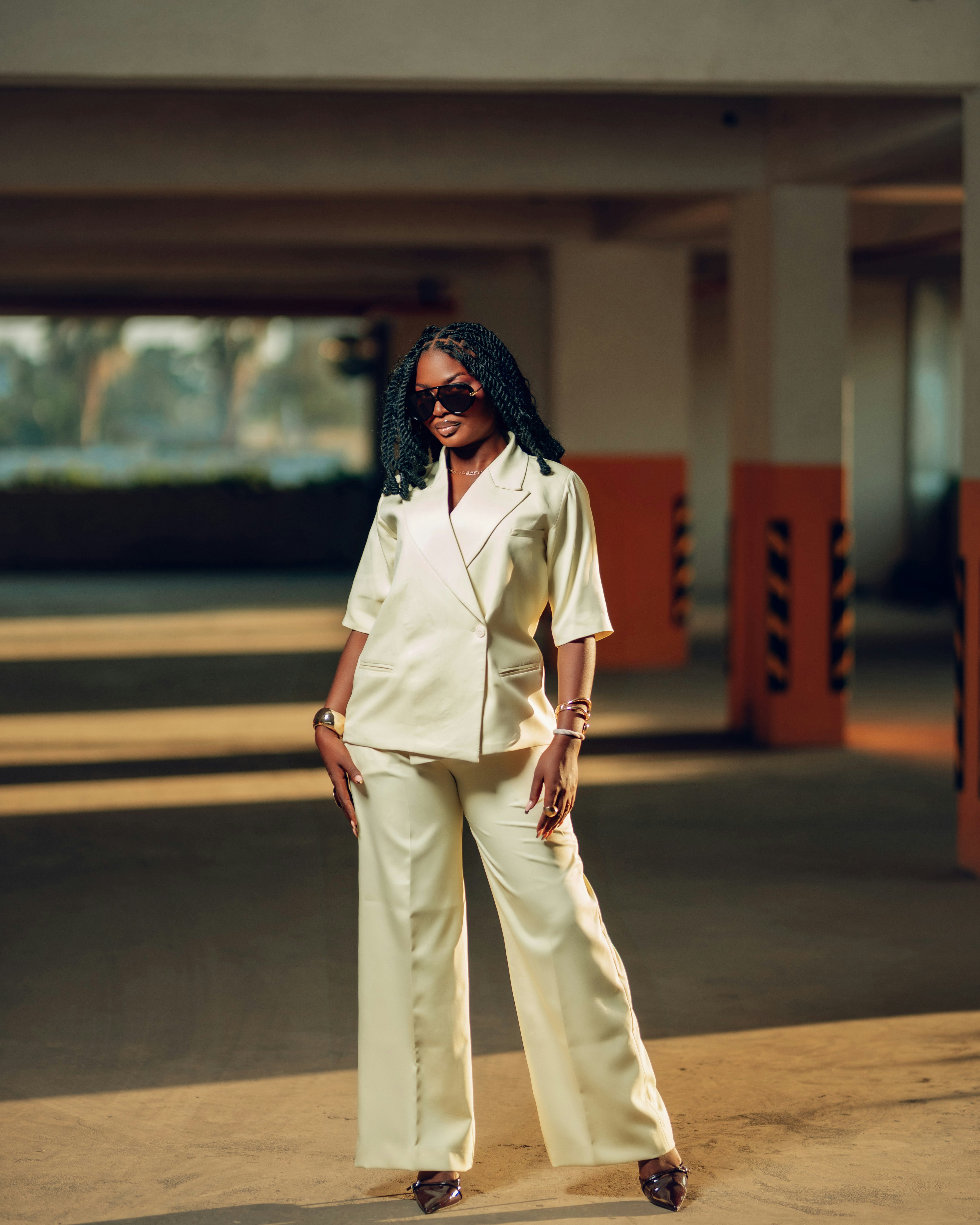Woman in a cream suit posing in a parking garage.