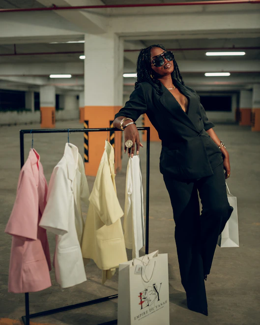 Woman in black suit poses near clothing rack