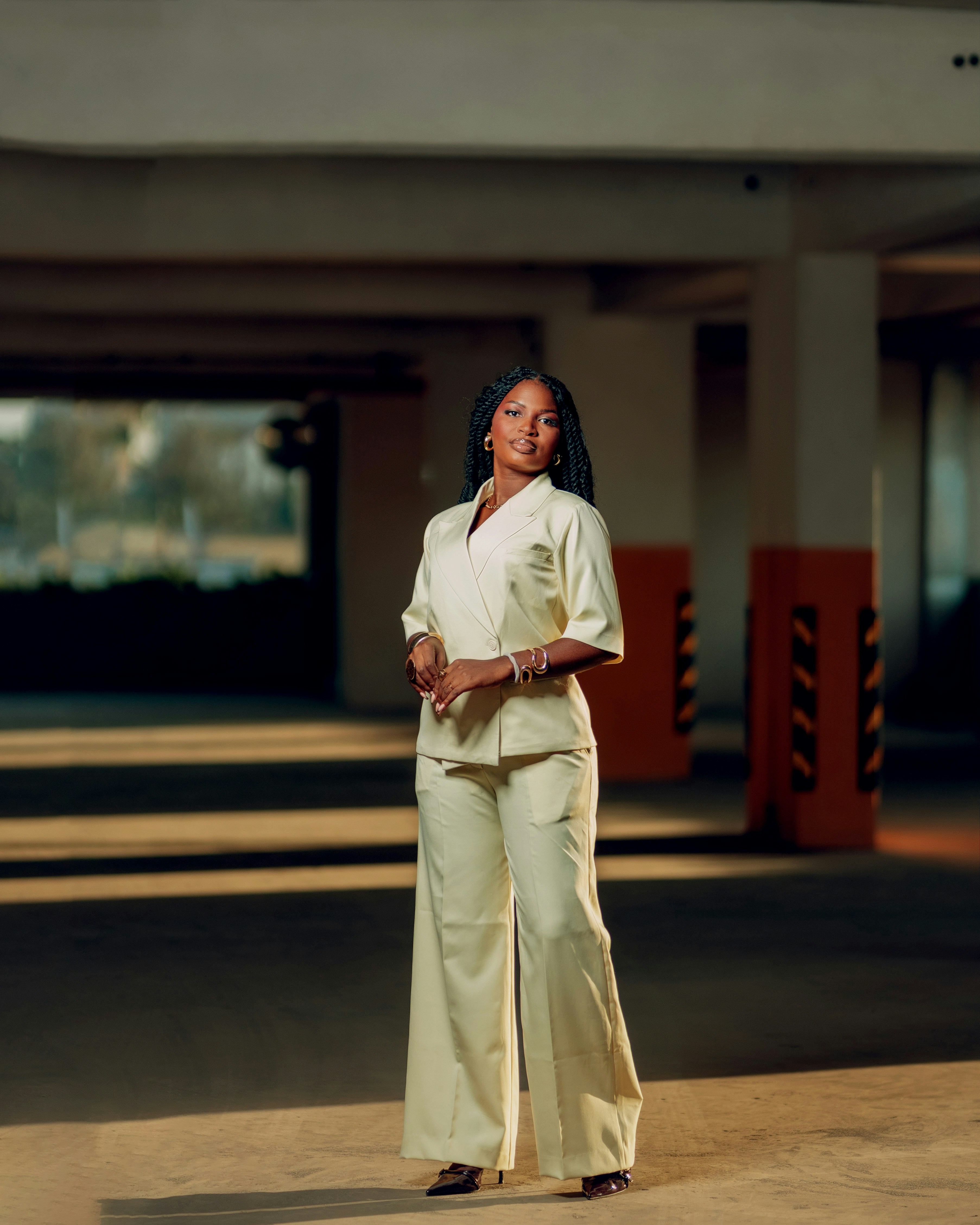 A woman stands in a dimly lit parking garage.