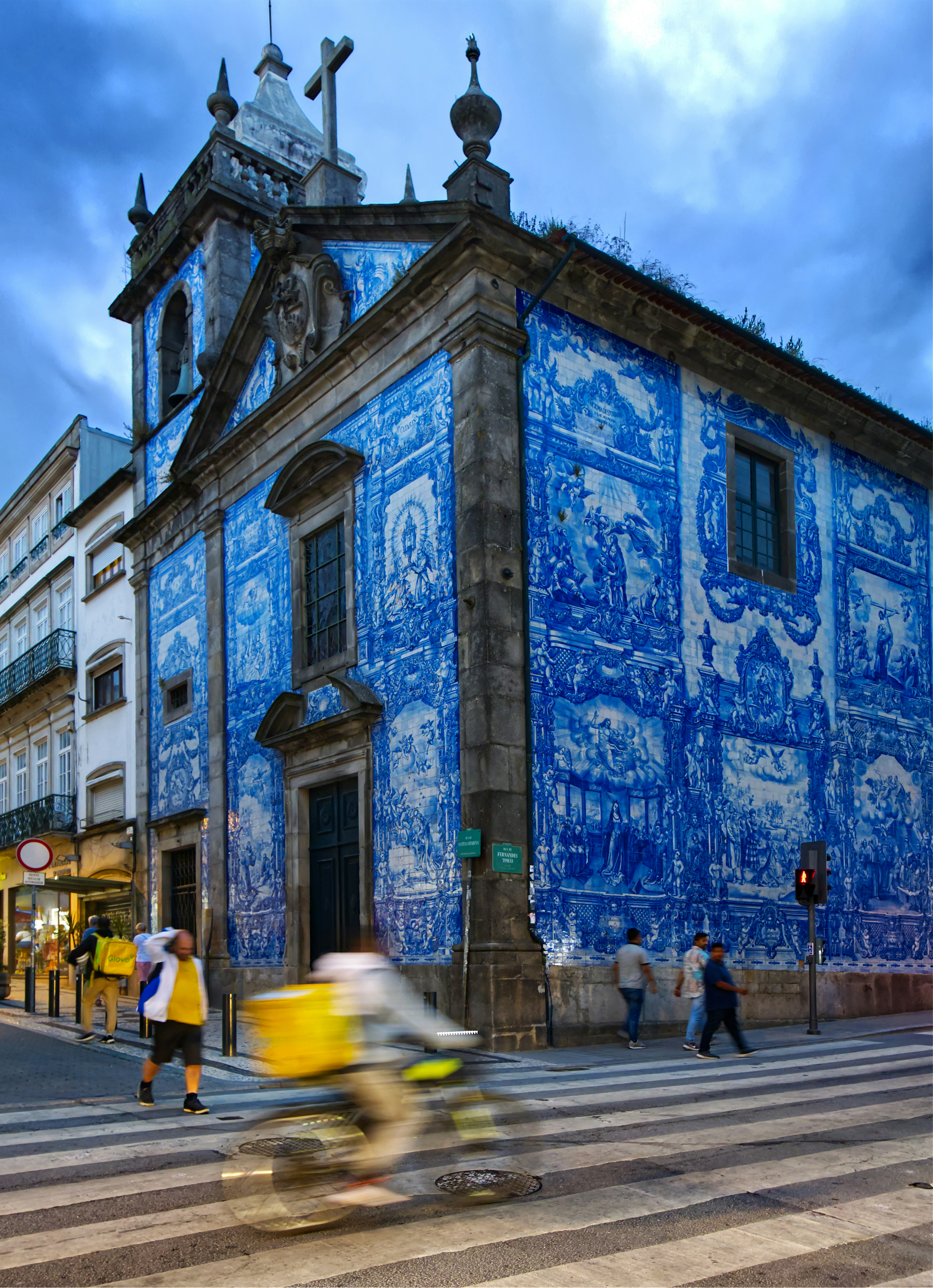 Building covered in blue and white tiles with people walking.