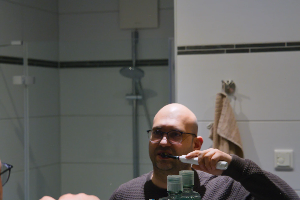 İllüstratif görsel: Man brushing teeth in front of a bathroom mirror.