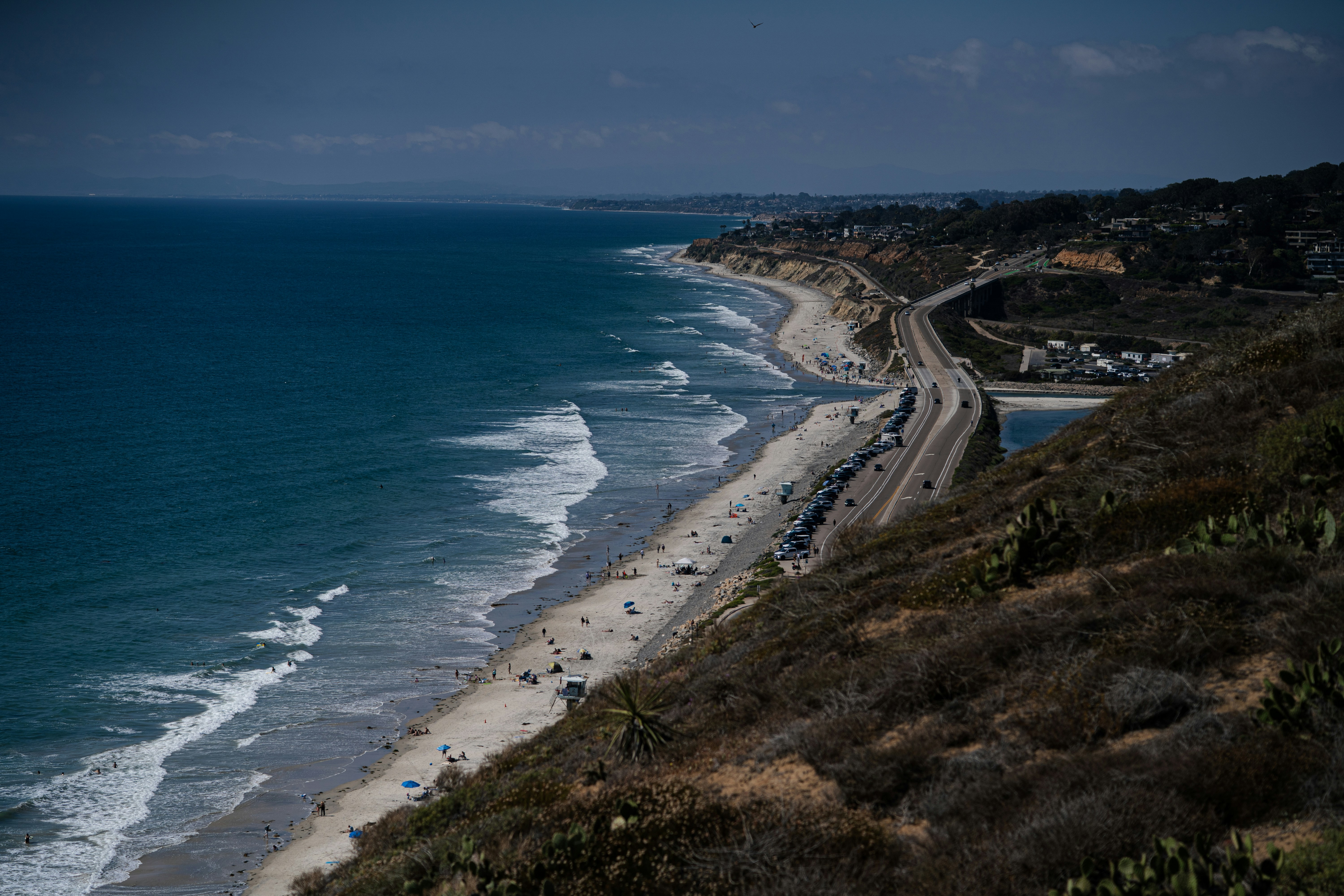 La carretera costera discurre junto a una playa de arena y el océano.