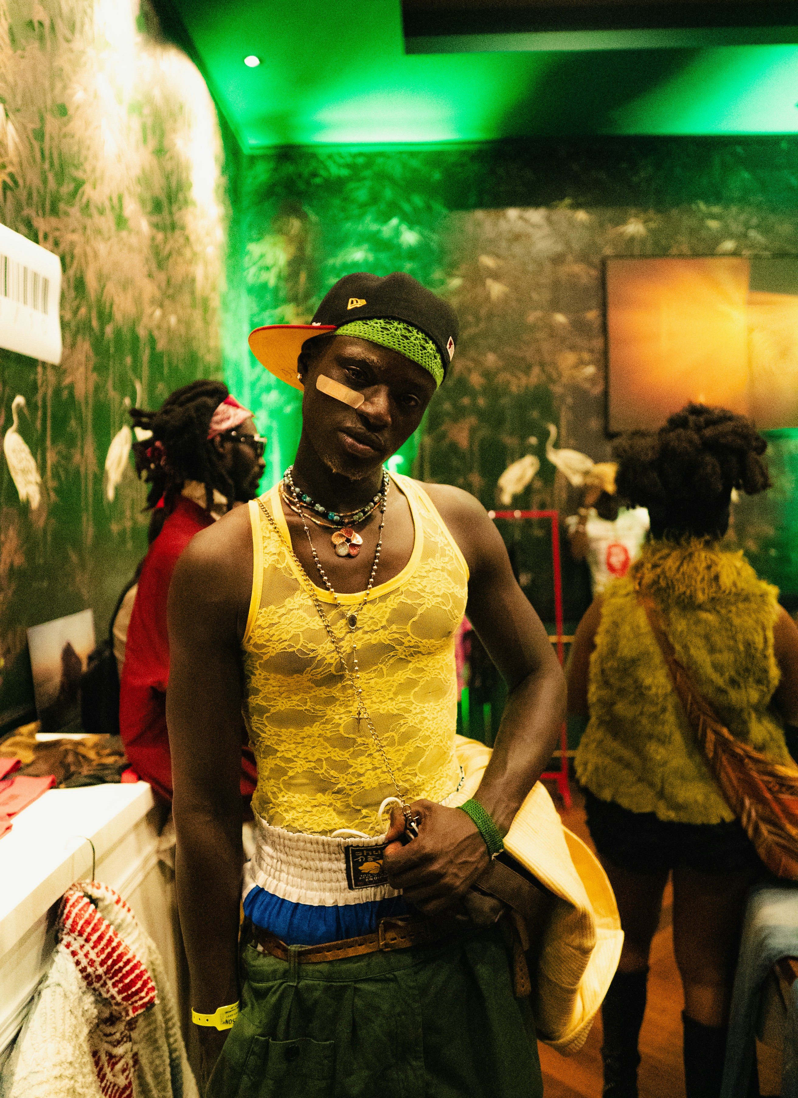 Pria dengan tank top kuning dan rok hijau dengan bandana.