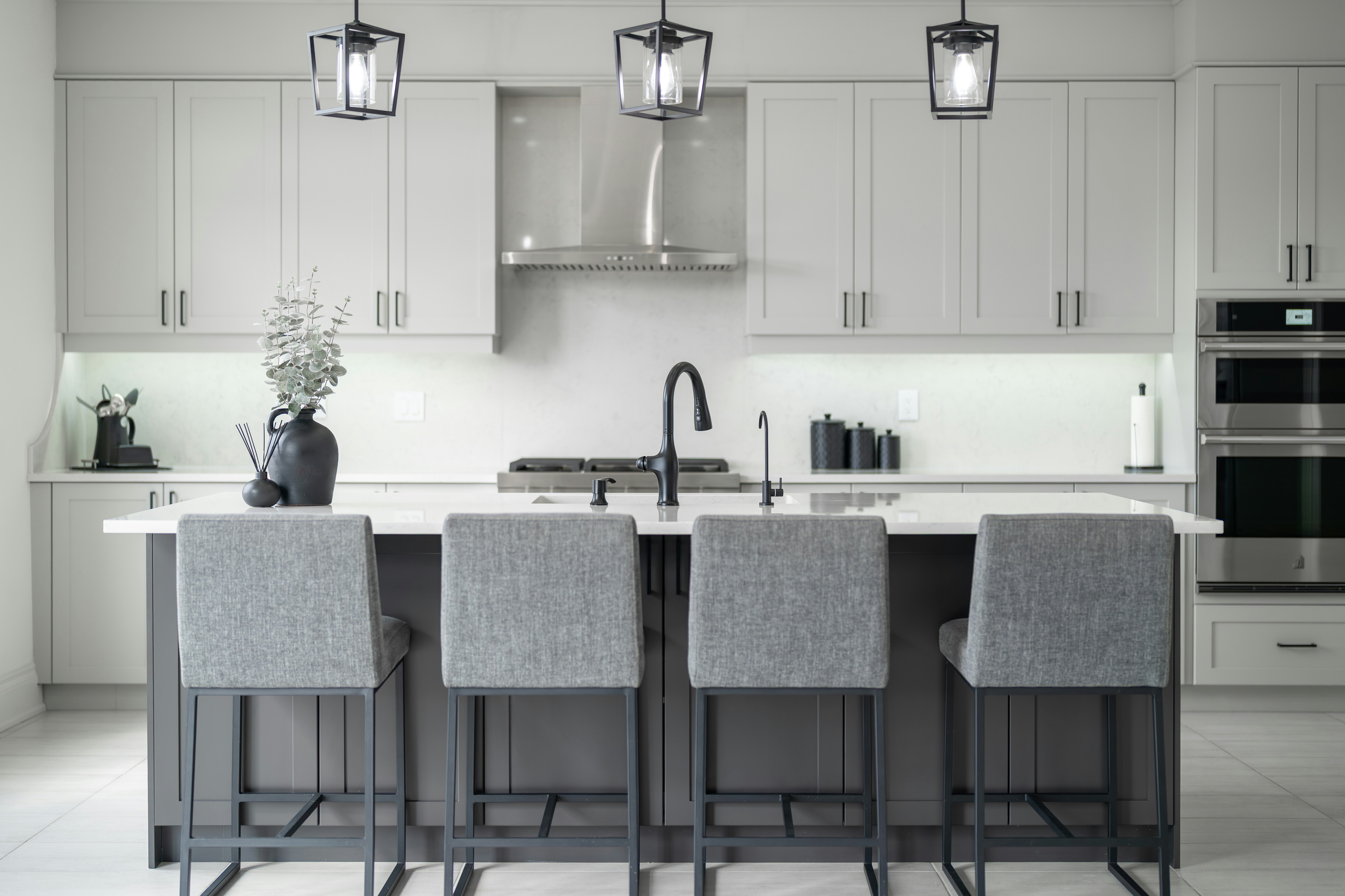 Modern kitchen island with four grey bar stools.