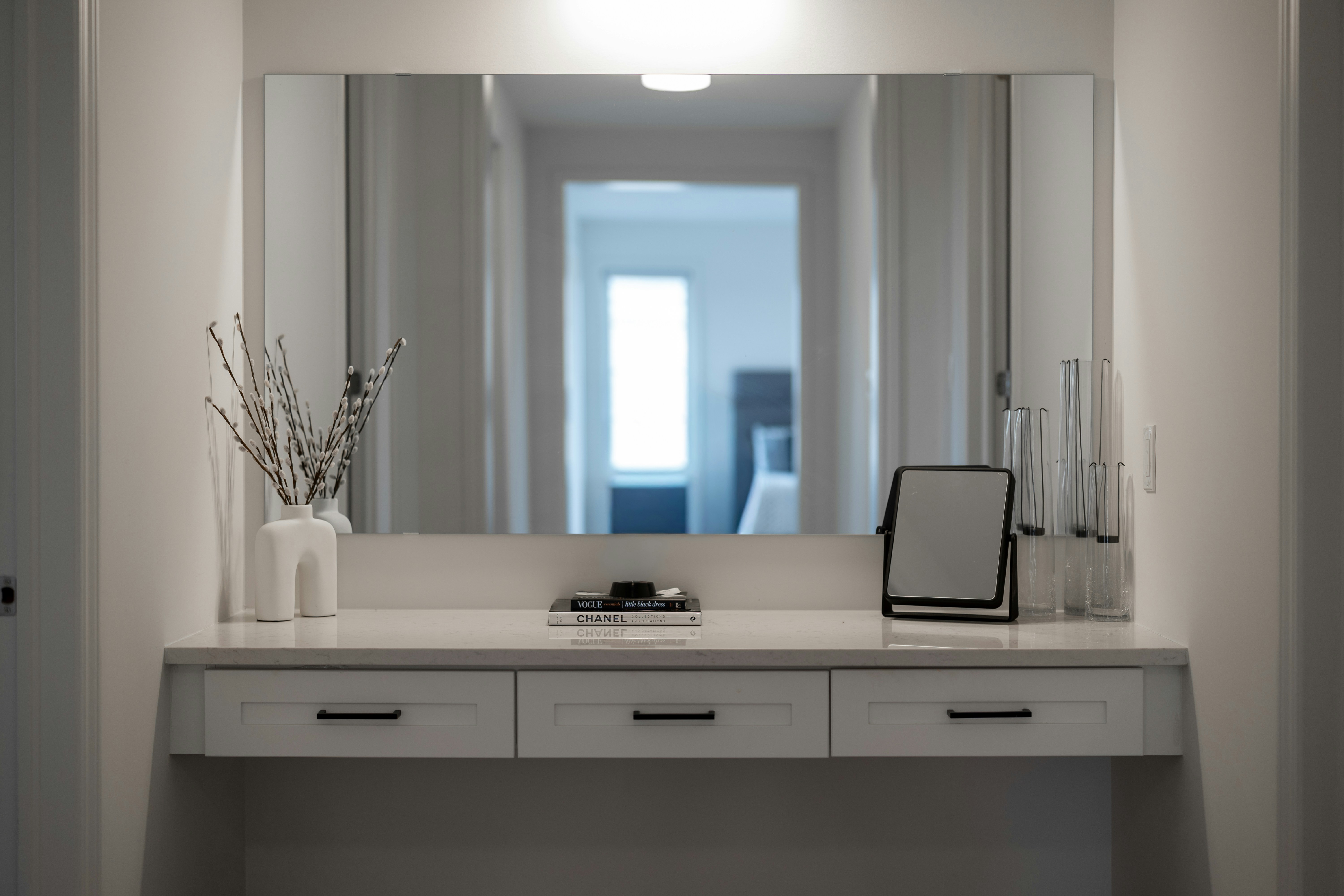 A modern vanity table with a large mirror and decor.