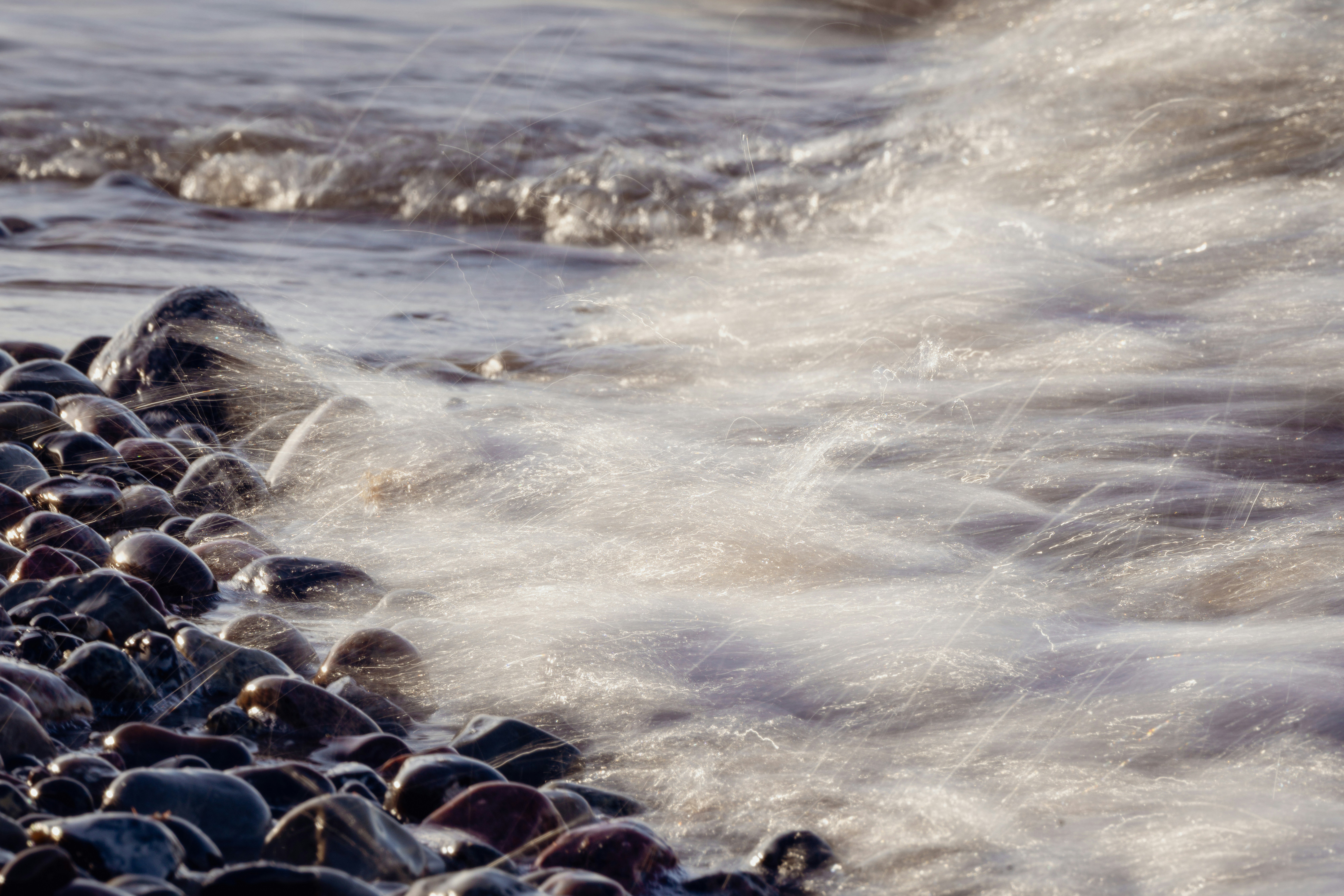 Waves washing over pebbles on a rocky shore.