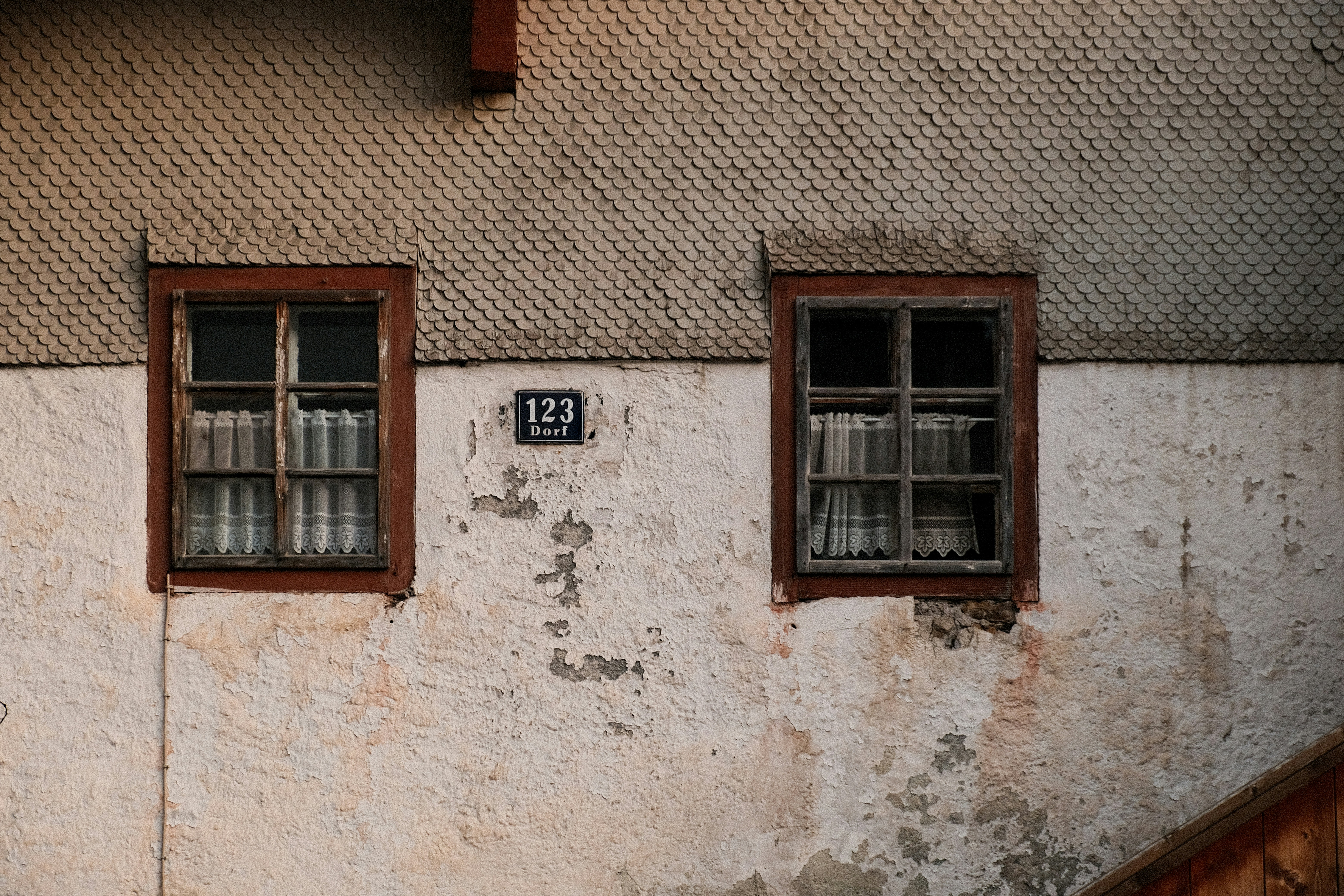 Zwei alte Fenster an einer verwitterten Gebäudefassade.
