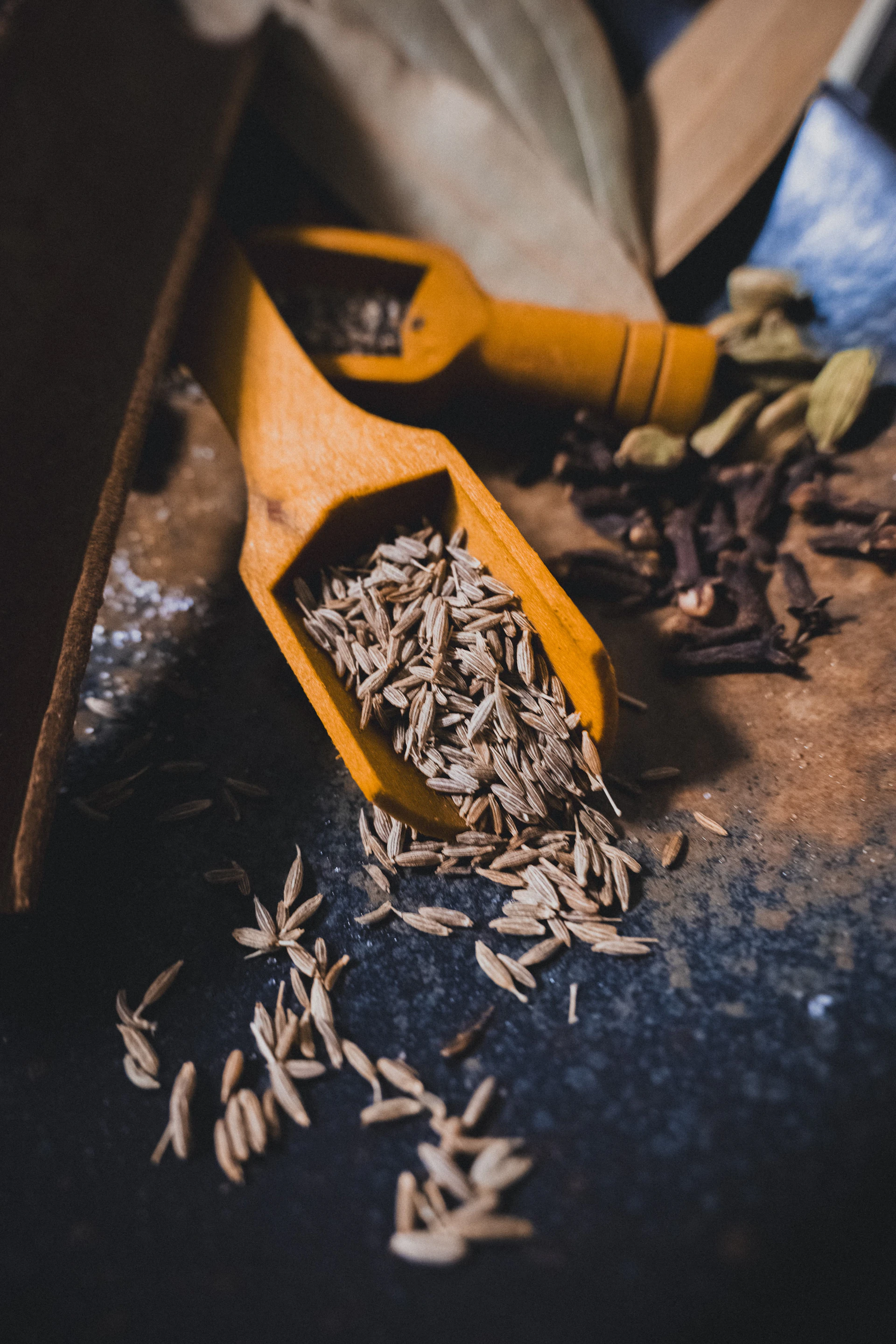 Wooden scoops filled with cumin seeds and spices