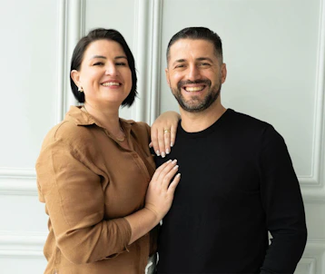 A smiling couple poses for a studio portrait.