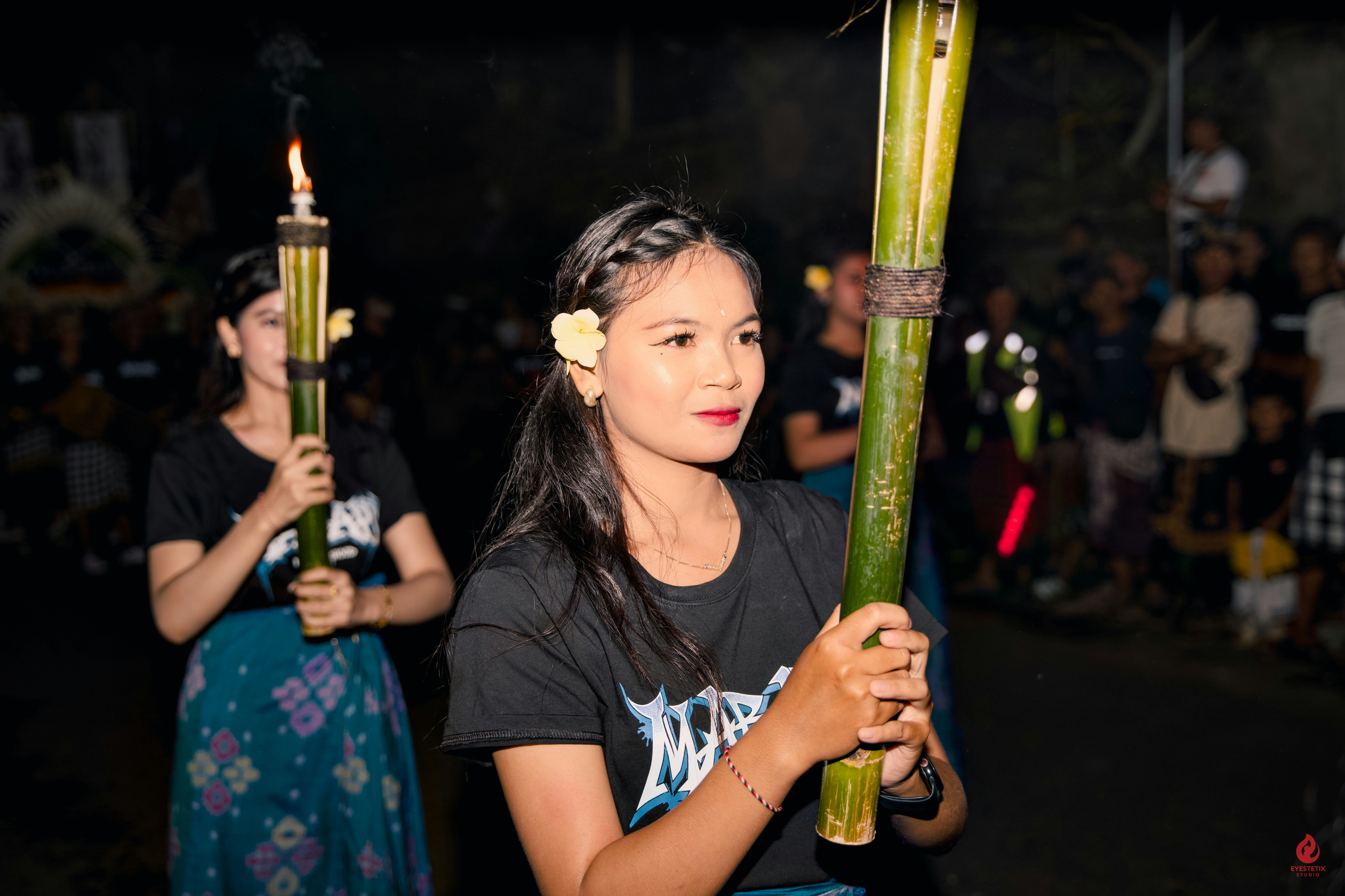 Young women in traditional attire holding bamboo torches