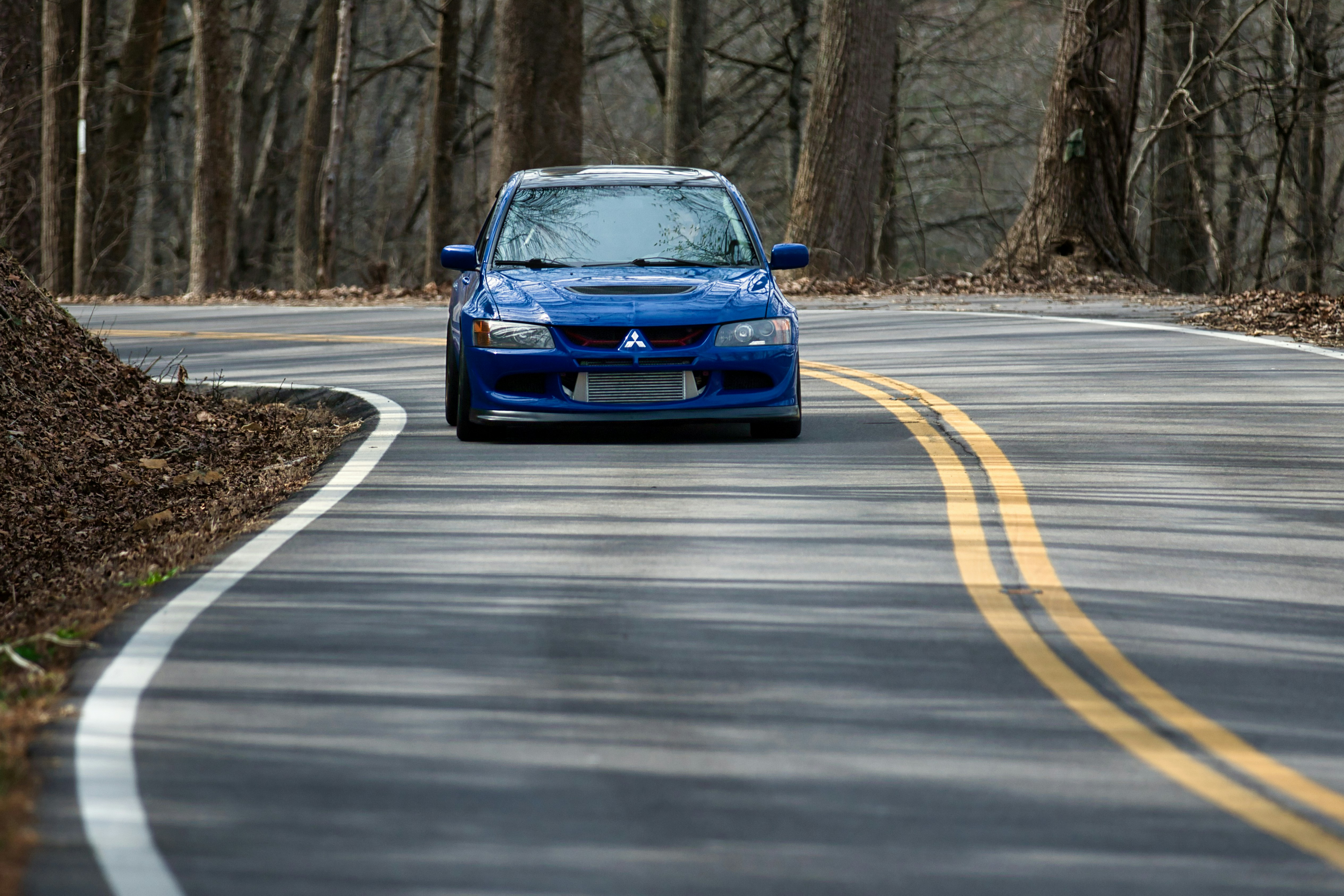 Blaues Auto fährt auf einer kurvigen Straße