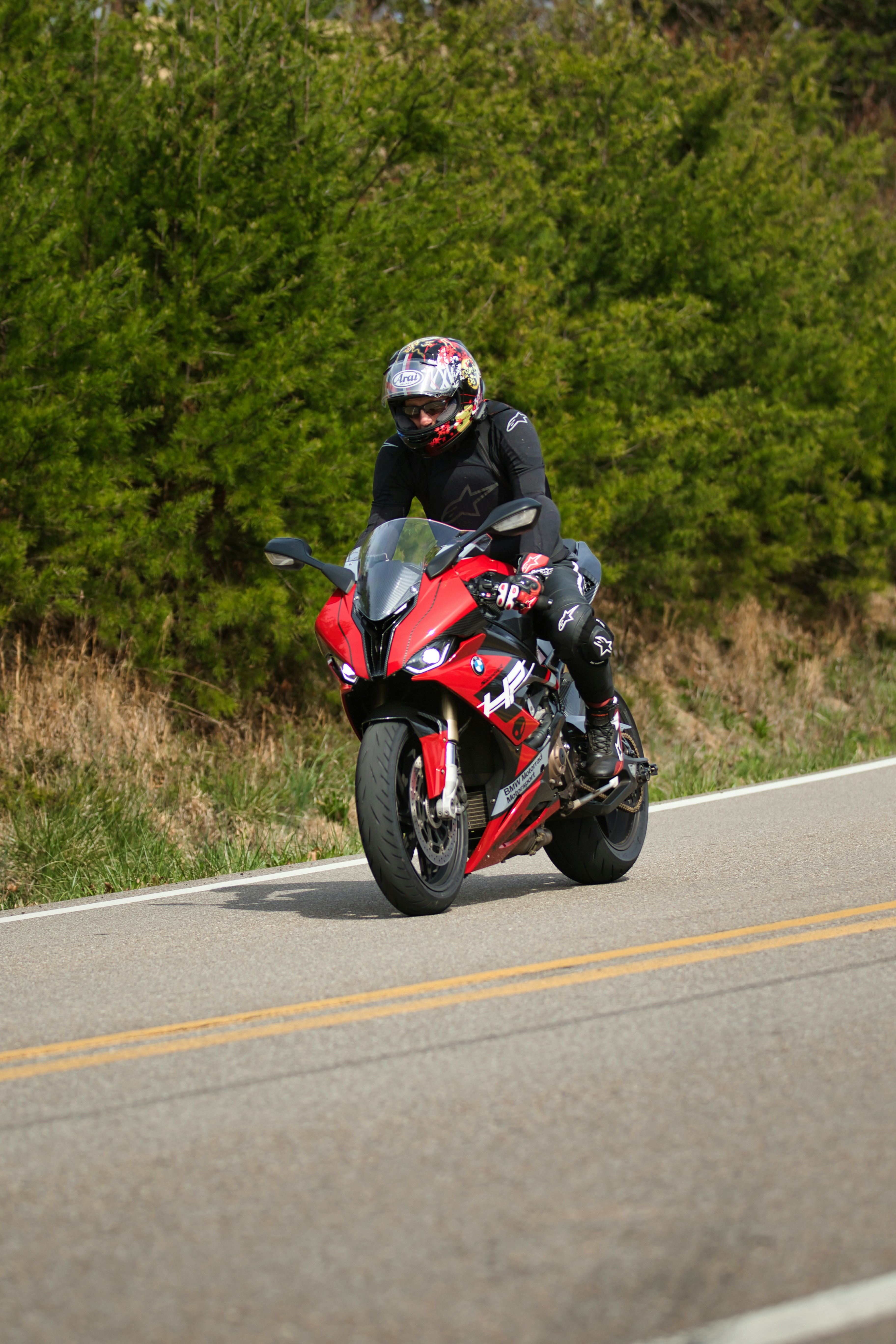 Fahrer auf einem roten Sportmotorrad auf asphaltierter Straße.