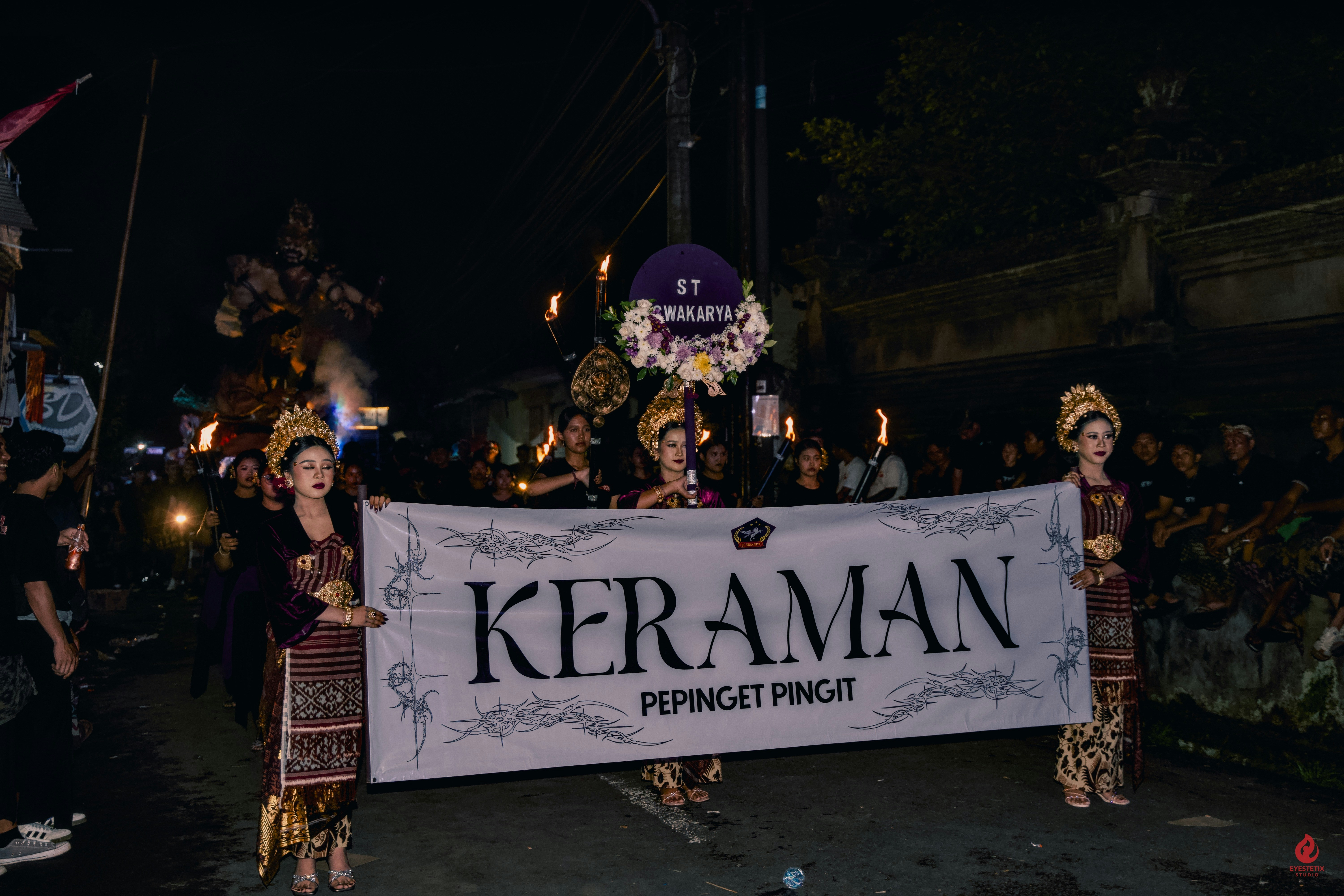 People in traditional attire hold a banner at night.