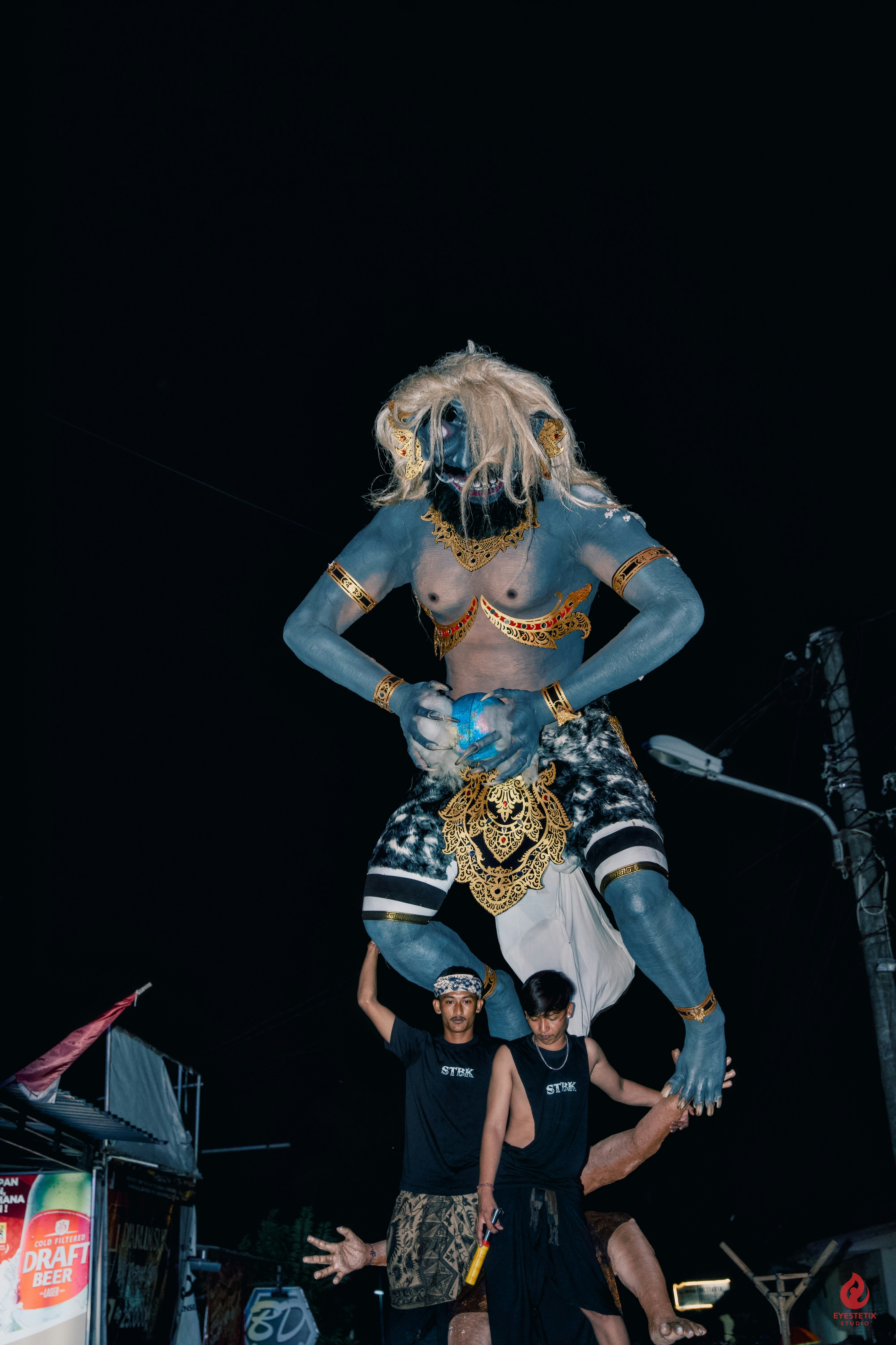 Giant blue demon statue held aloft by men at night photo – Free Night ...