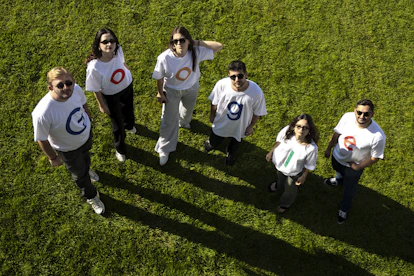 Six people in matching t-shirts on grass