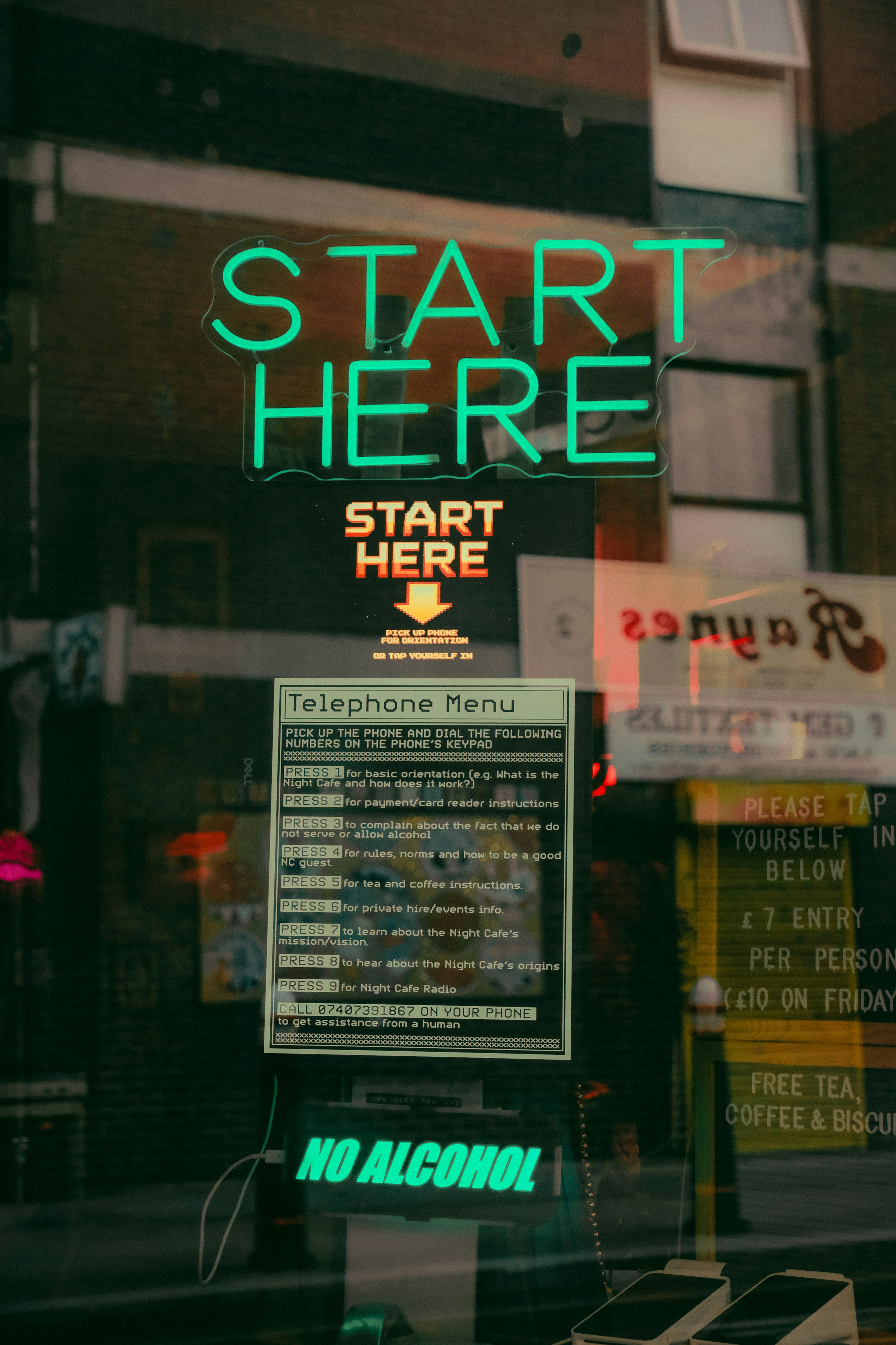 Neon "start here" sign above telephone menu.