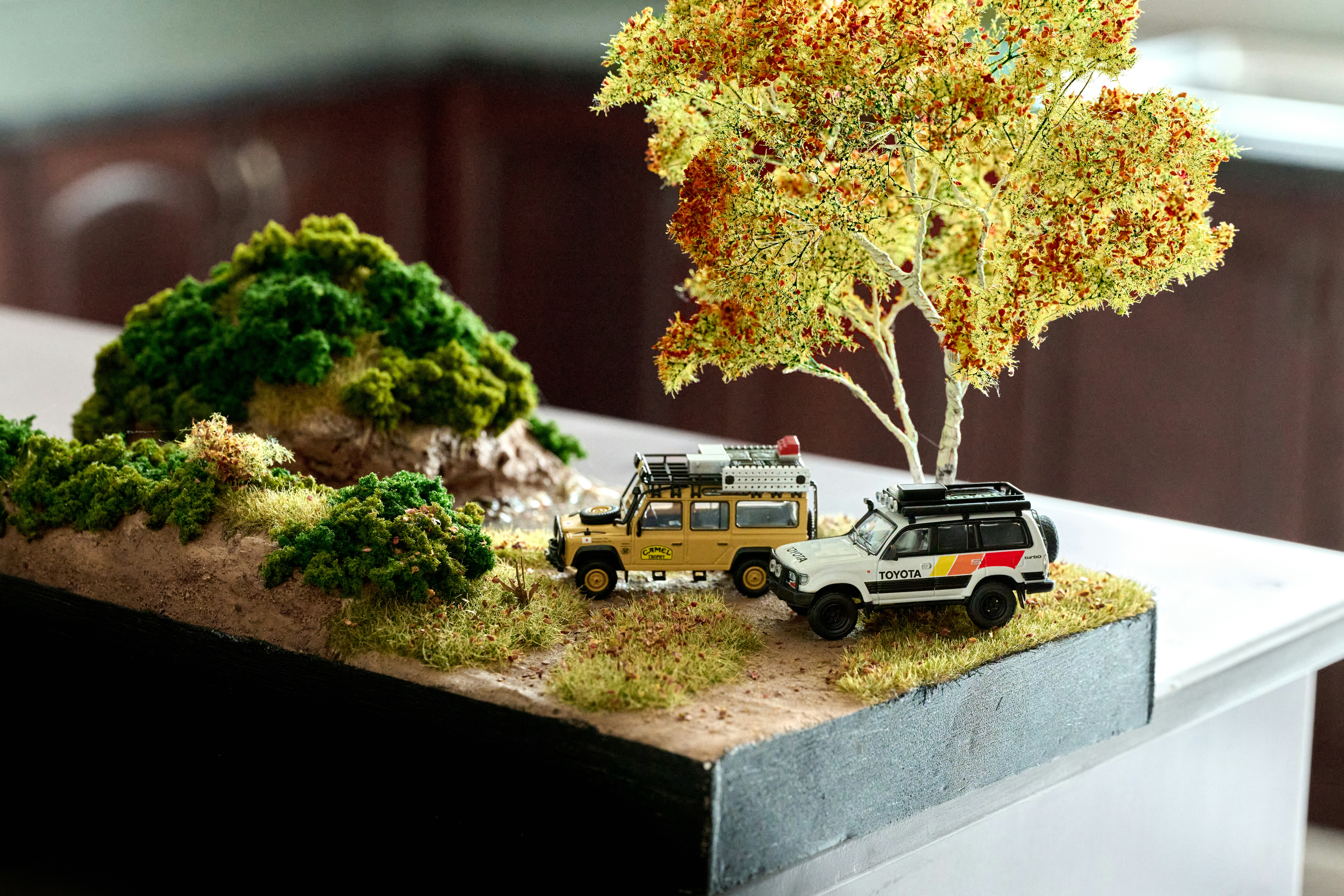 Zwei Spielzeug-SUVs parkten auf einer Diorama-Landschaft.