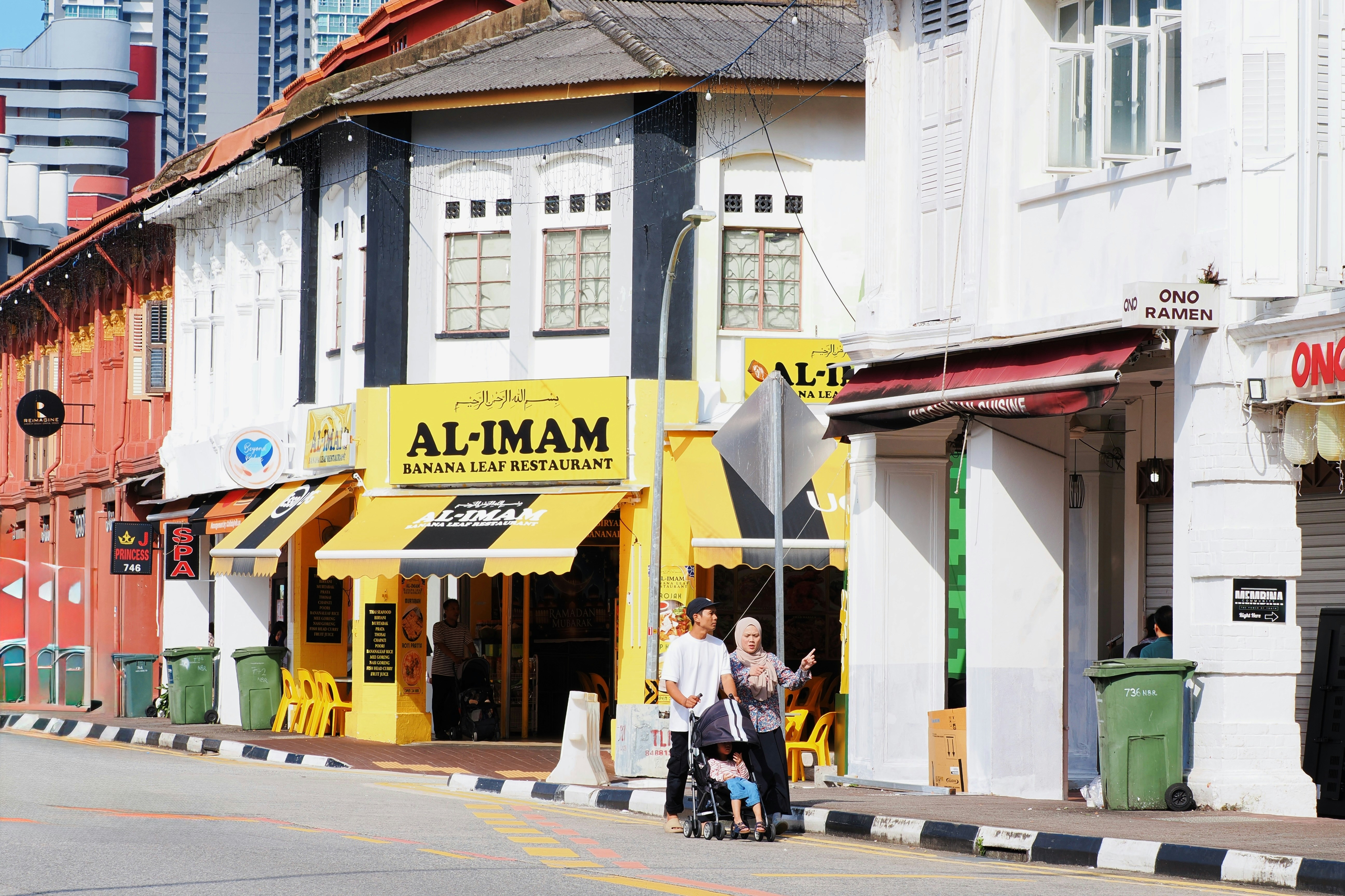 Orang-orang berjalan melewati toko-toko di jalan yang cerah