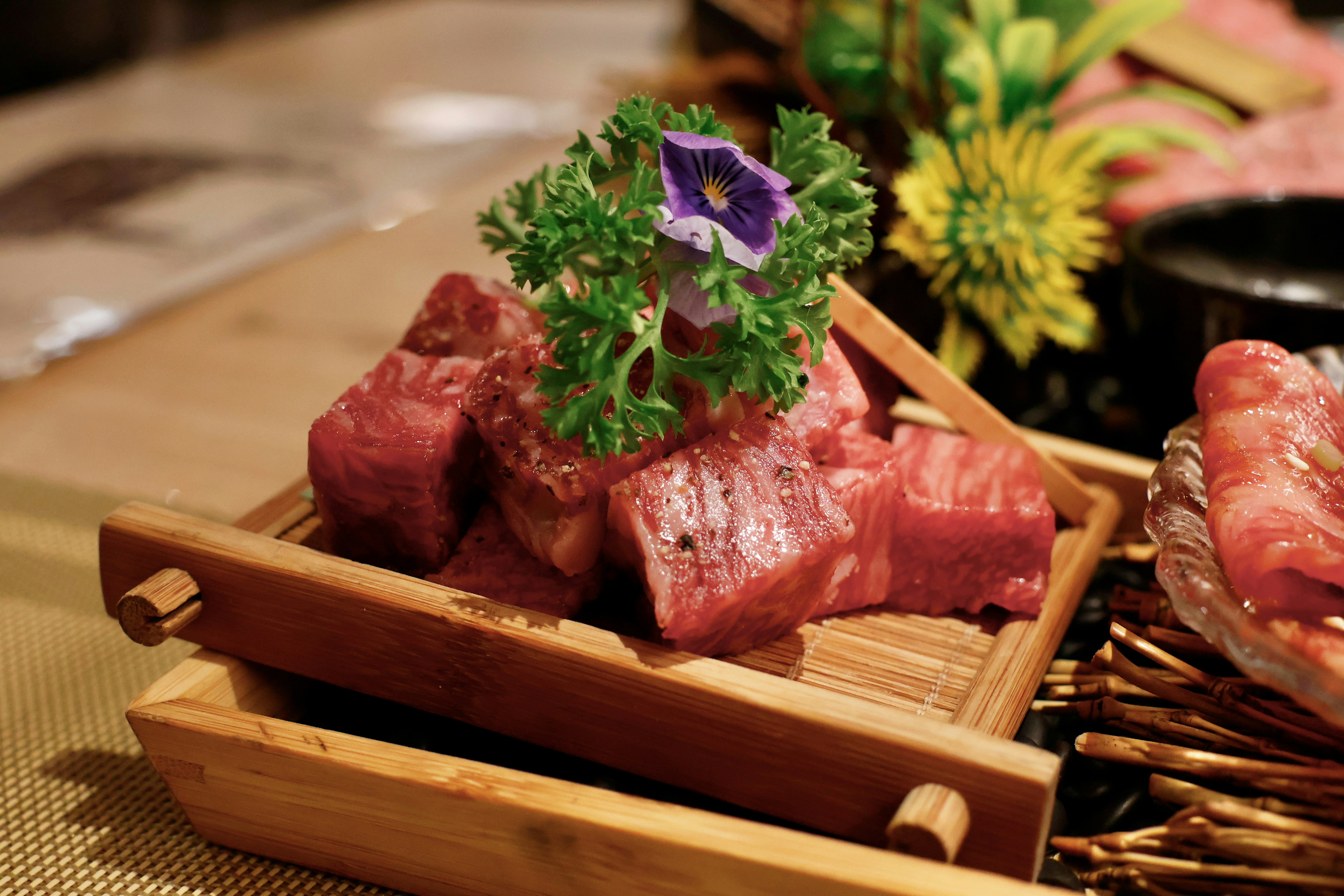 Diced raw beef garnished with parsley and a purple flower.