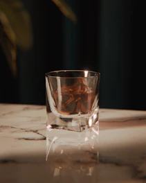 A glass of whiskey with ice on a marble surface