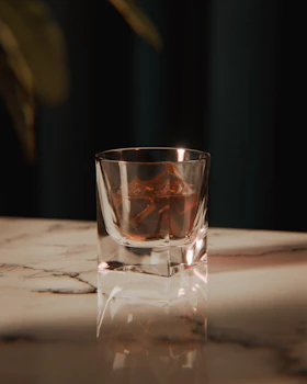 A glass of whiskey with ice on a marble surface