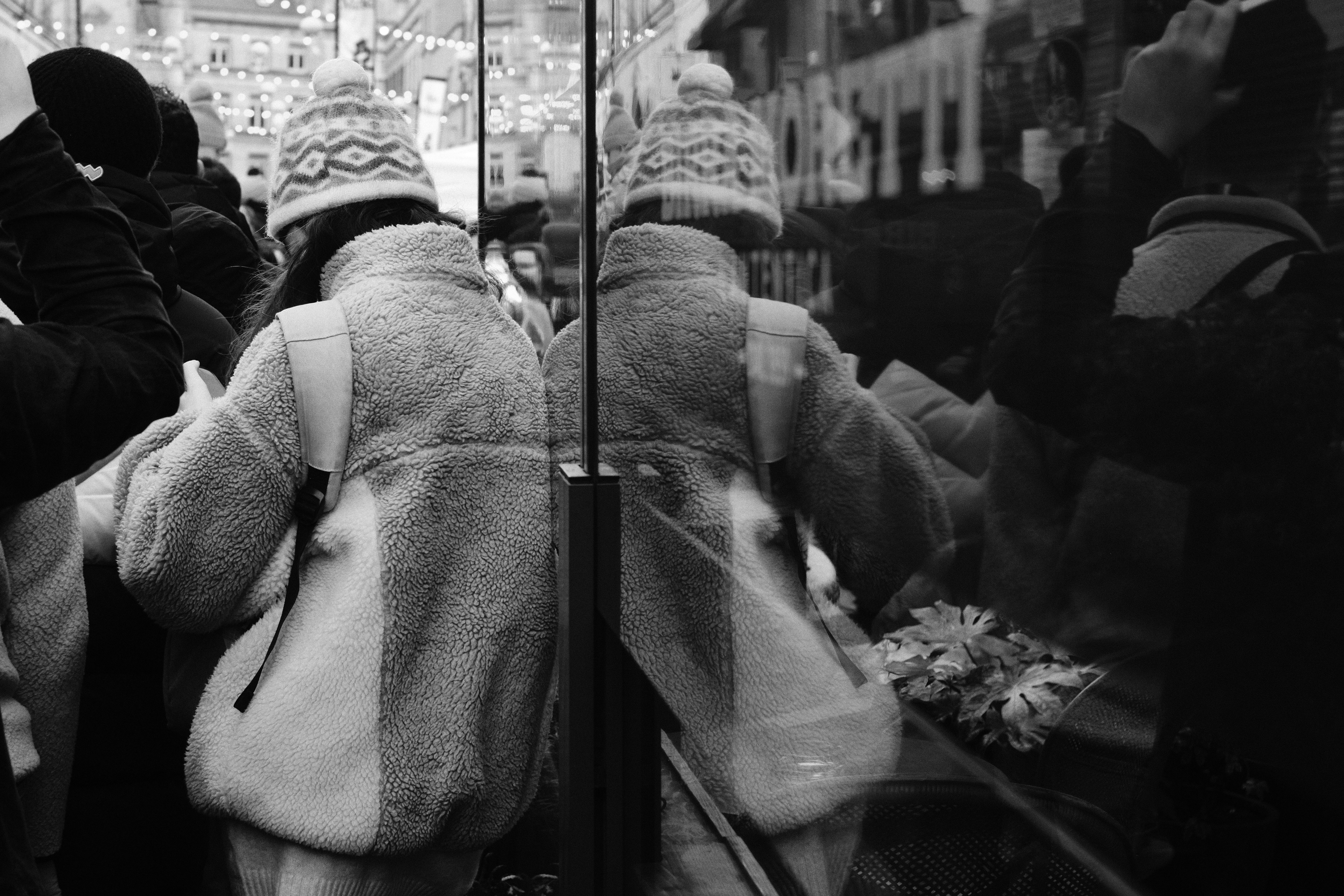 Woman in winter hat reflected in glass