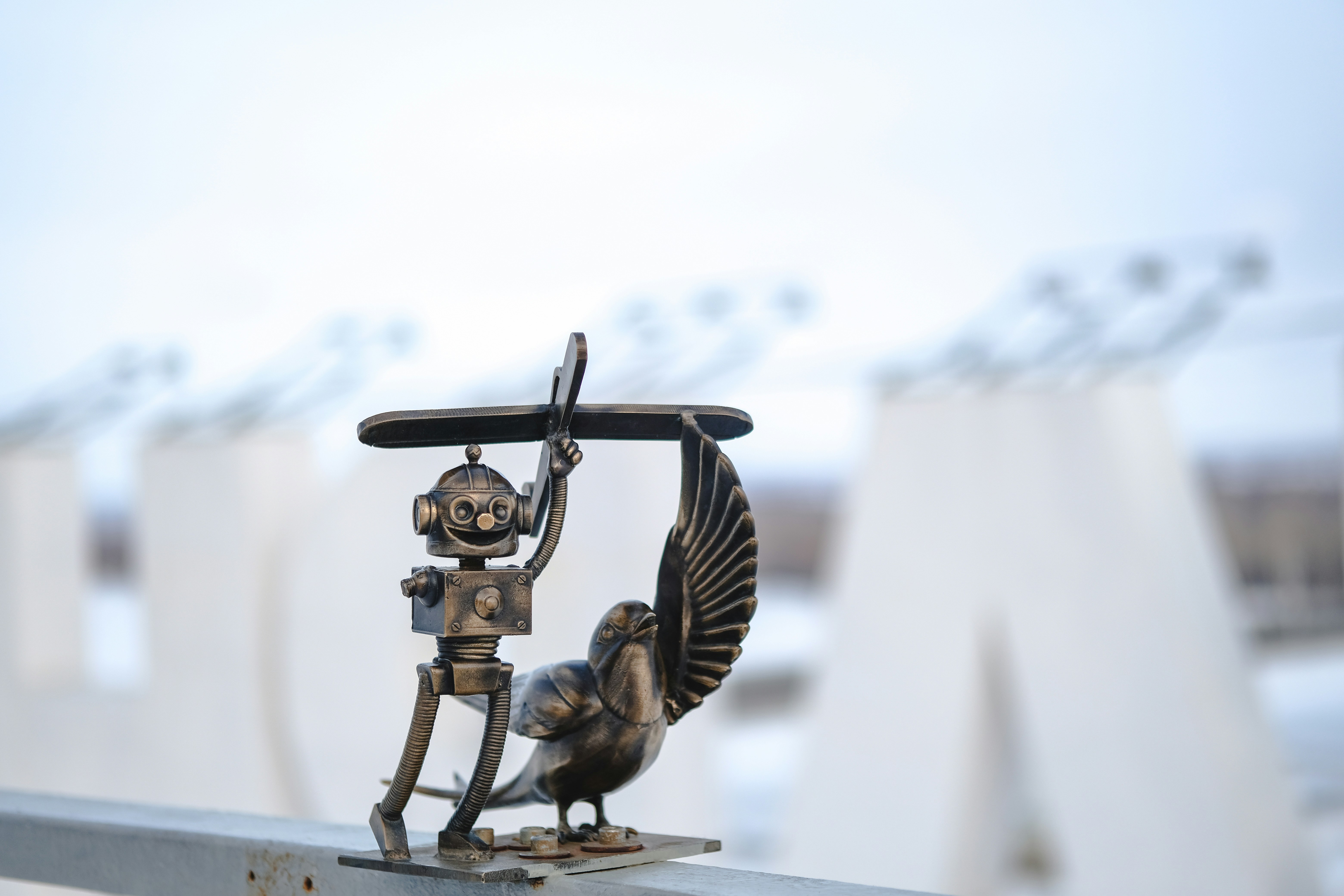 A small robot holding a propeller next to a bird.