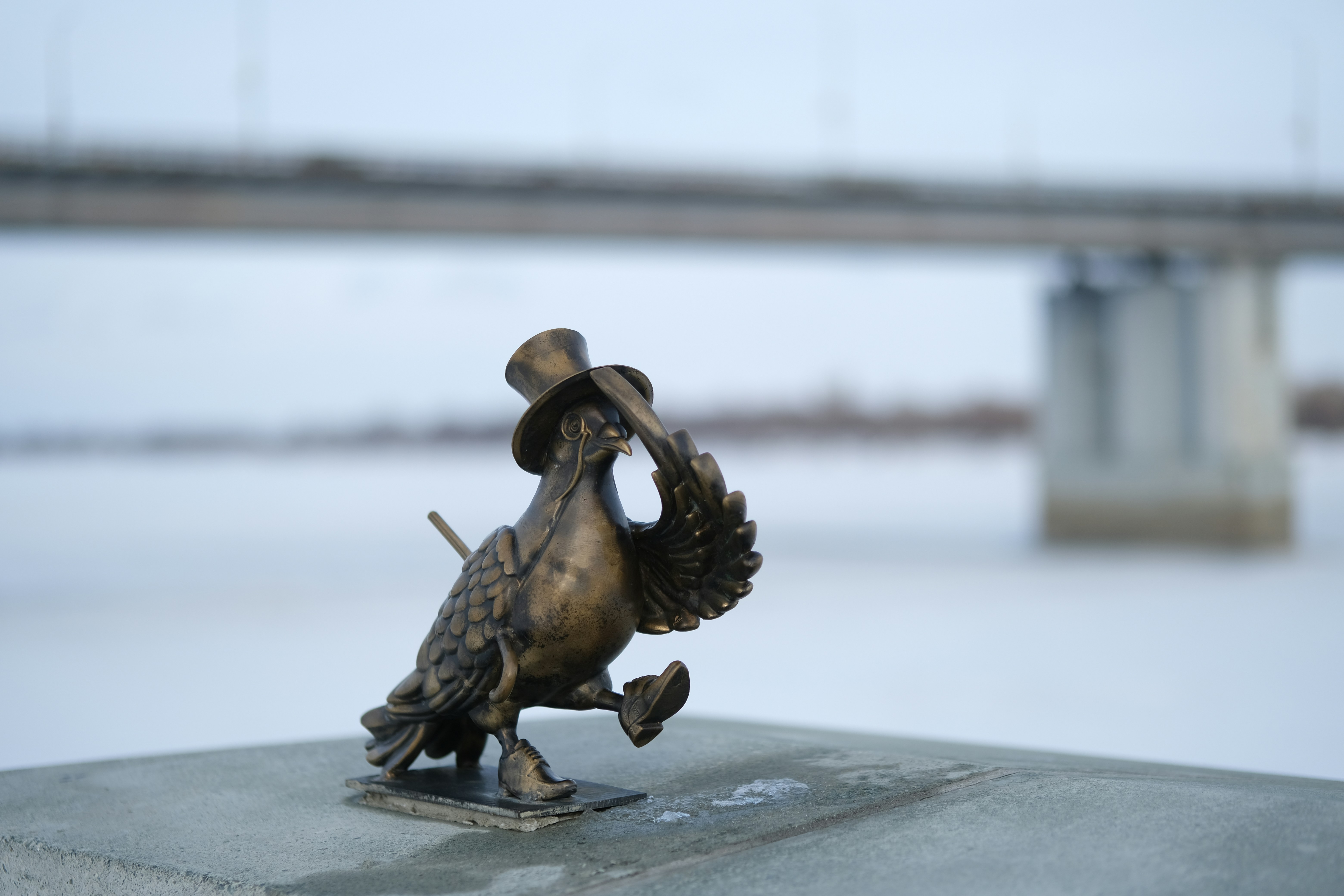 Bronze duck sculpture wearing a top hat by river