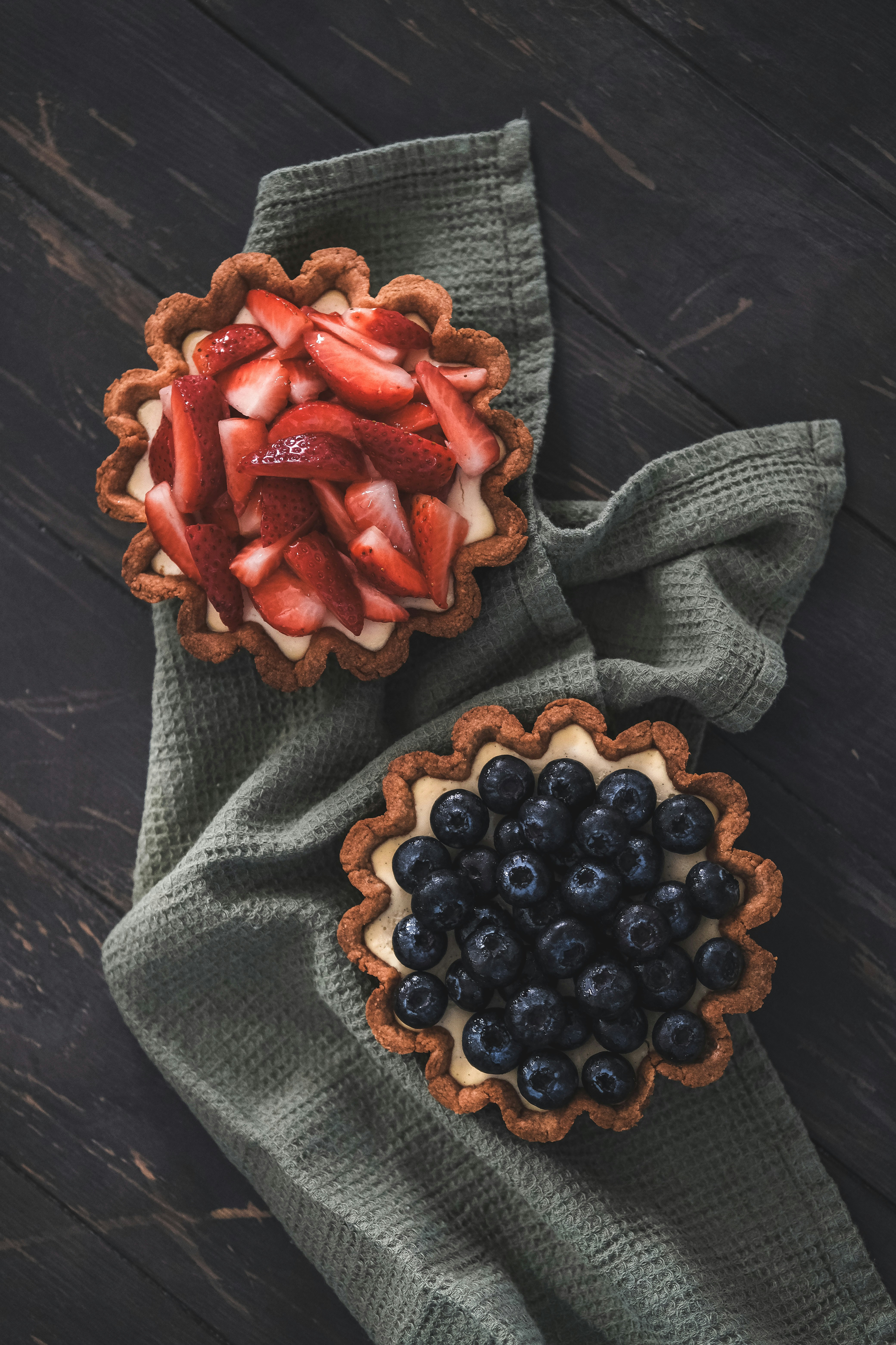 Two fruit tarts with strawberries and blueberries