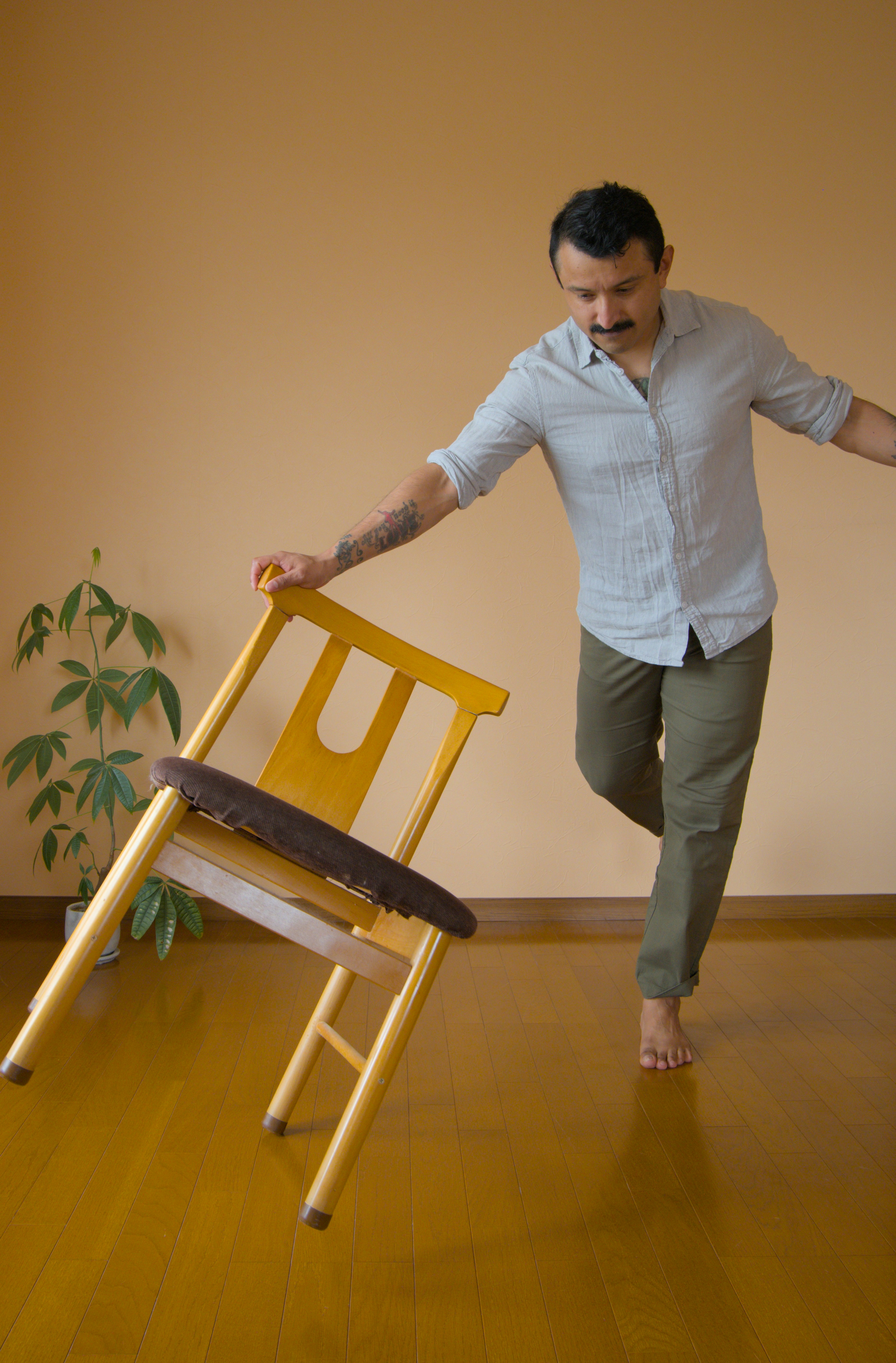 A man using a chair for support during a slow balance exercise.