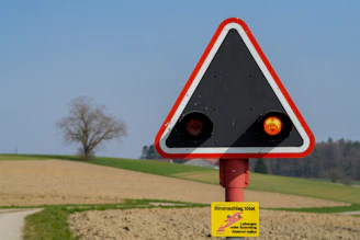 Warning sign with flashing lights near a tree