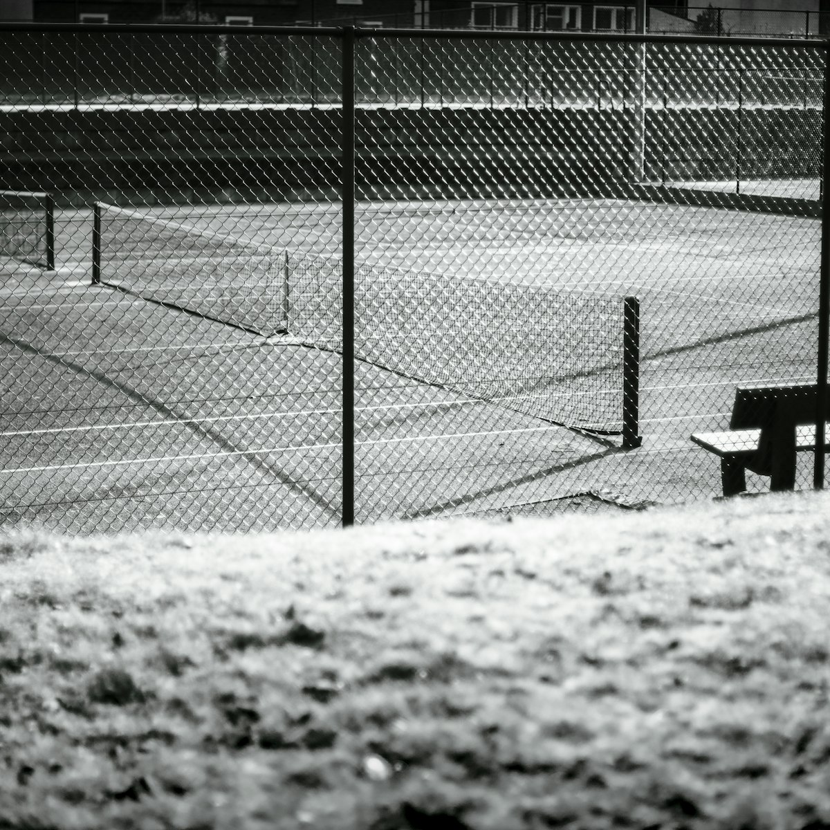 Schoolhouse Park tennis court and bench behind the fence line.