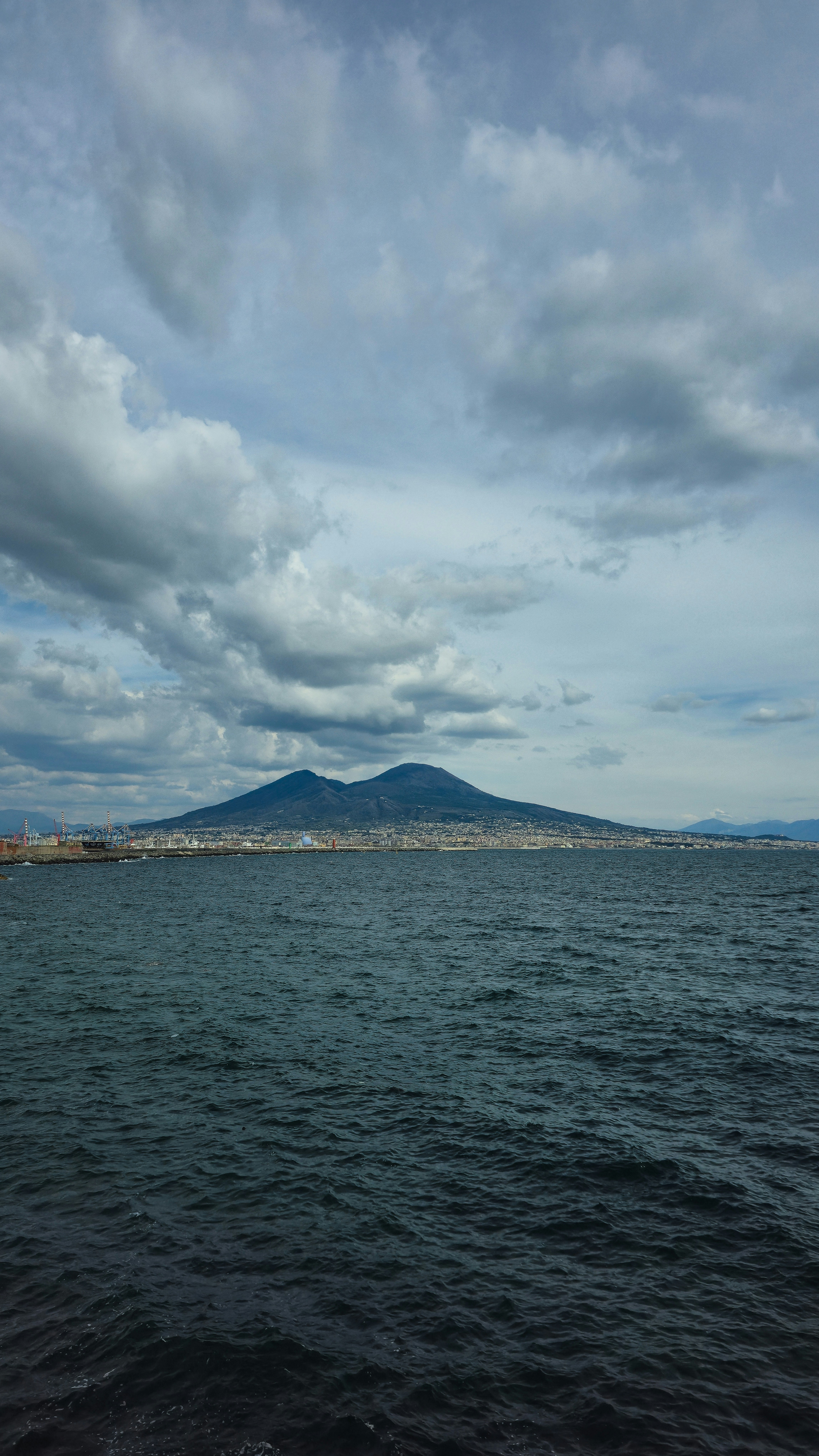 Volcano overlooking a city and the sea.