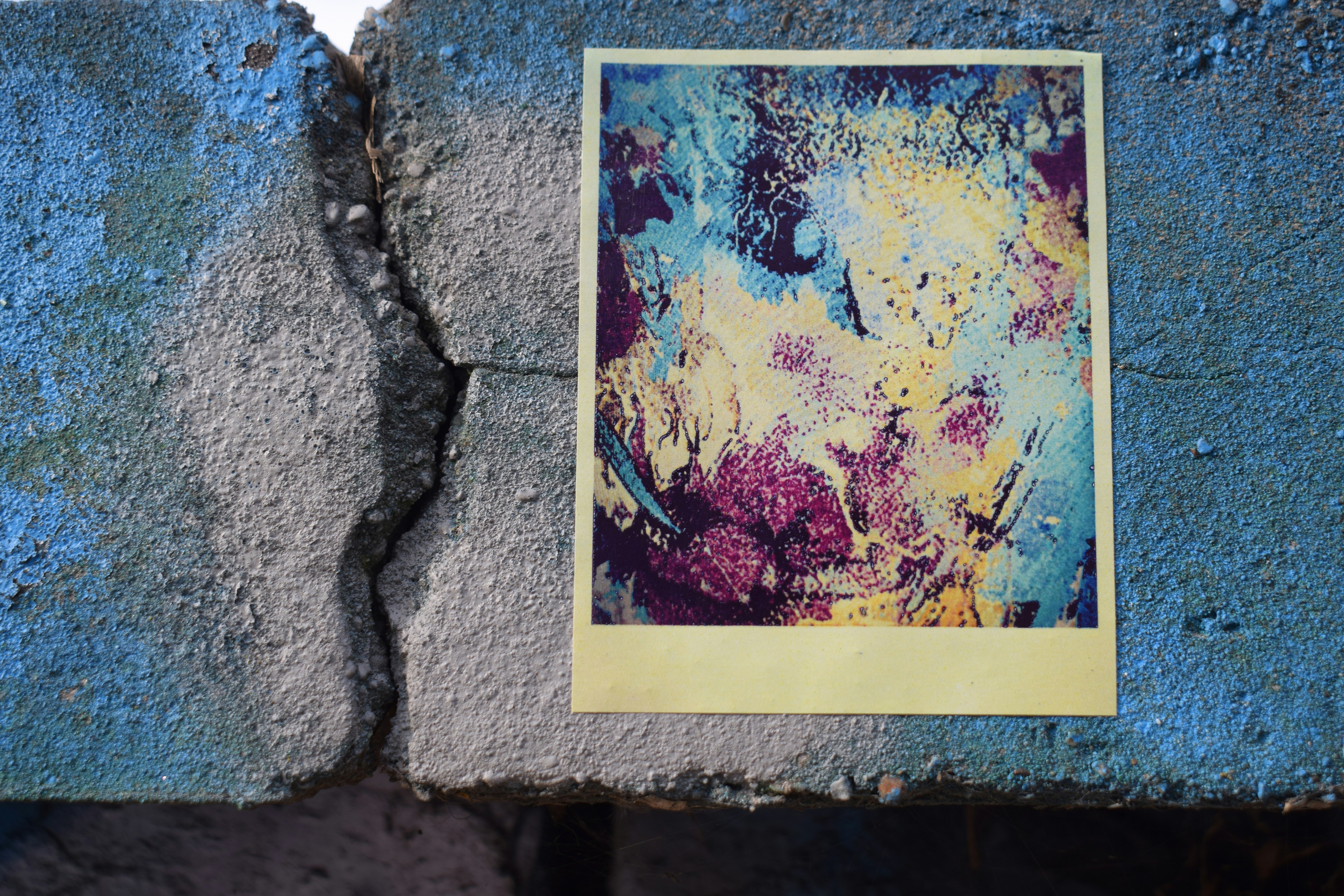 A colorful abstract painting on a cracked concrete wall