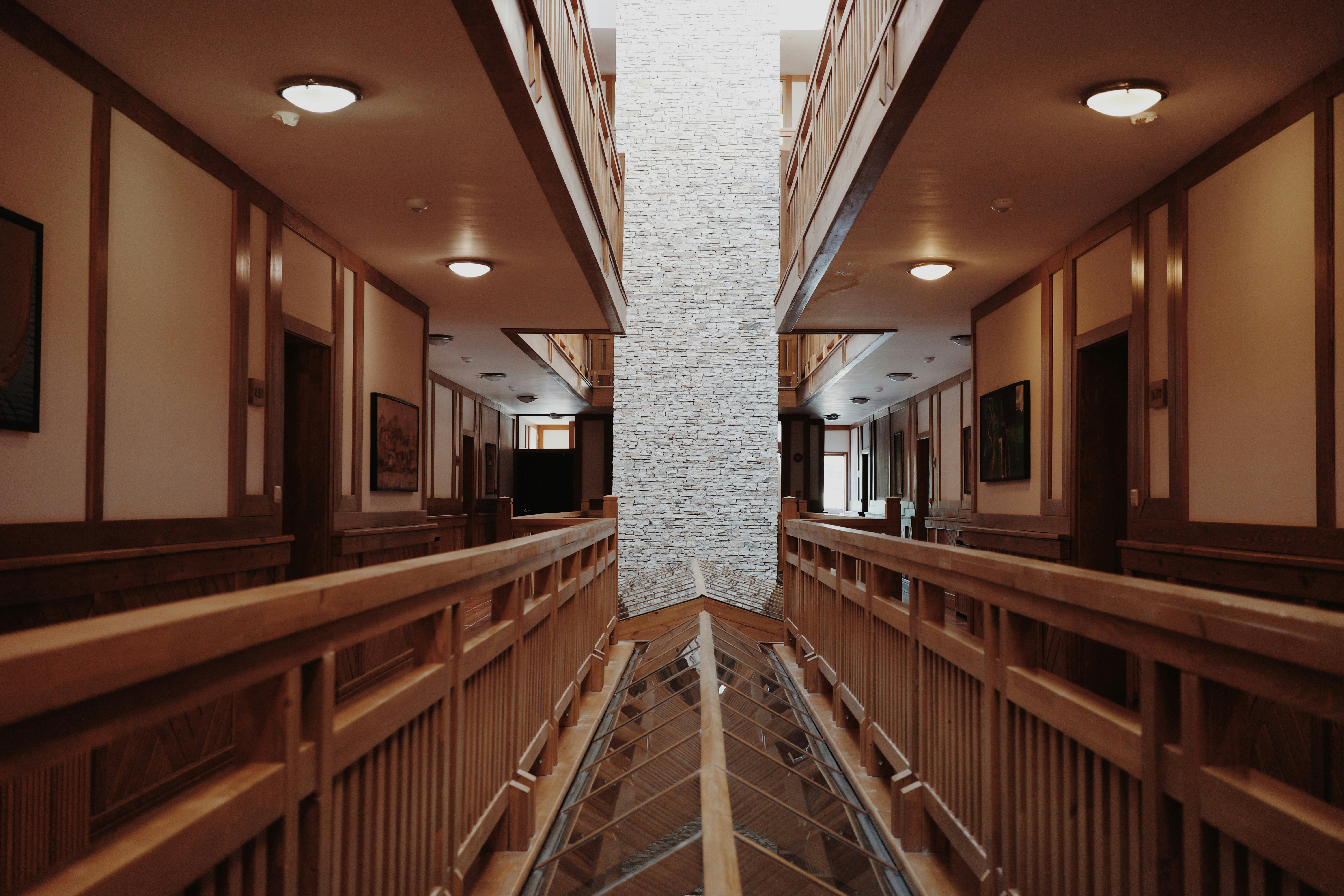 Symmetrical hotel corridor with wooden railings and doors.