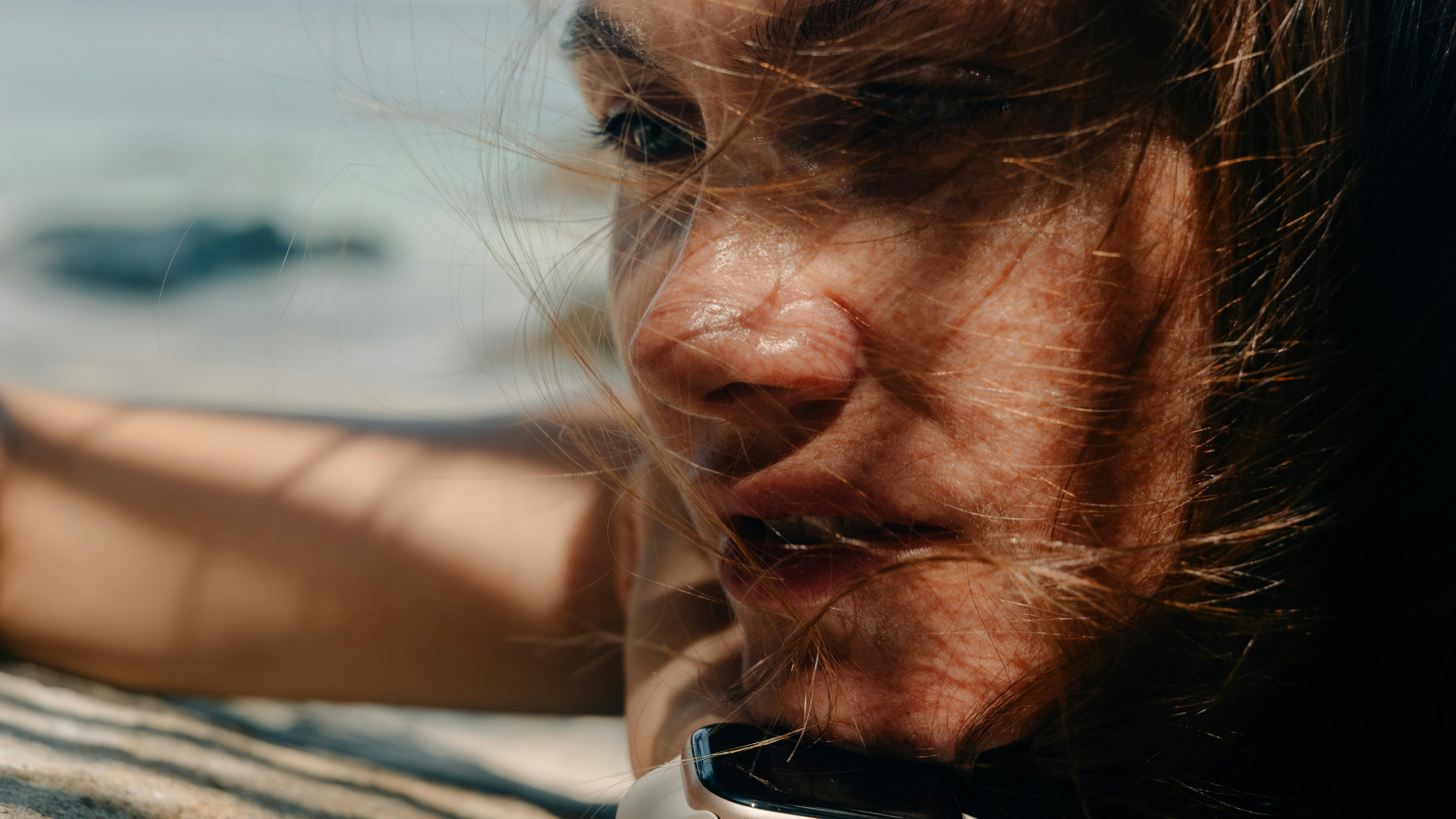 Close do rosto de uma mulher com cabelo bagunçado pelo vento.