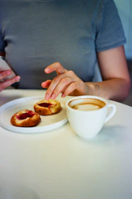 Person reaching for pastries next to coffee cup