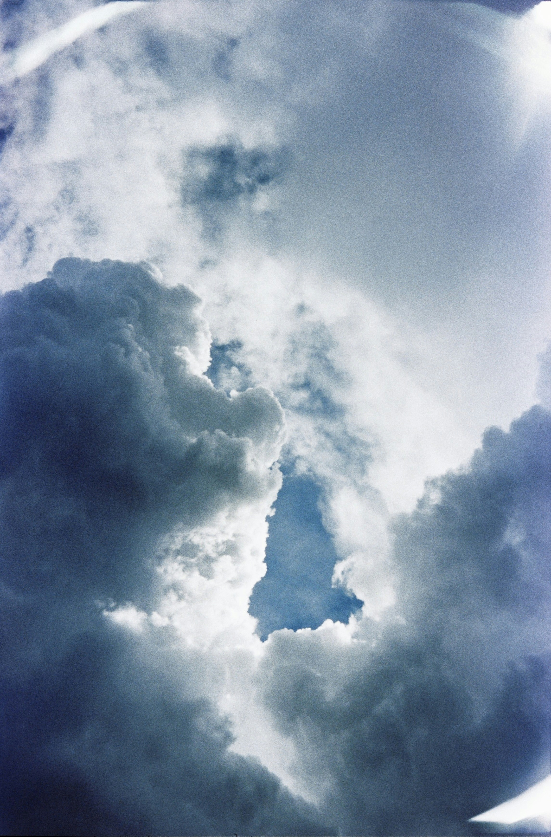 Dramatic stormy clouds with a clear blue sky opening.
