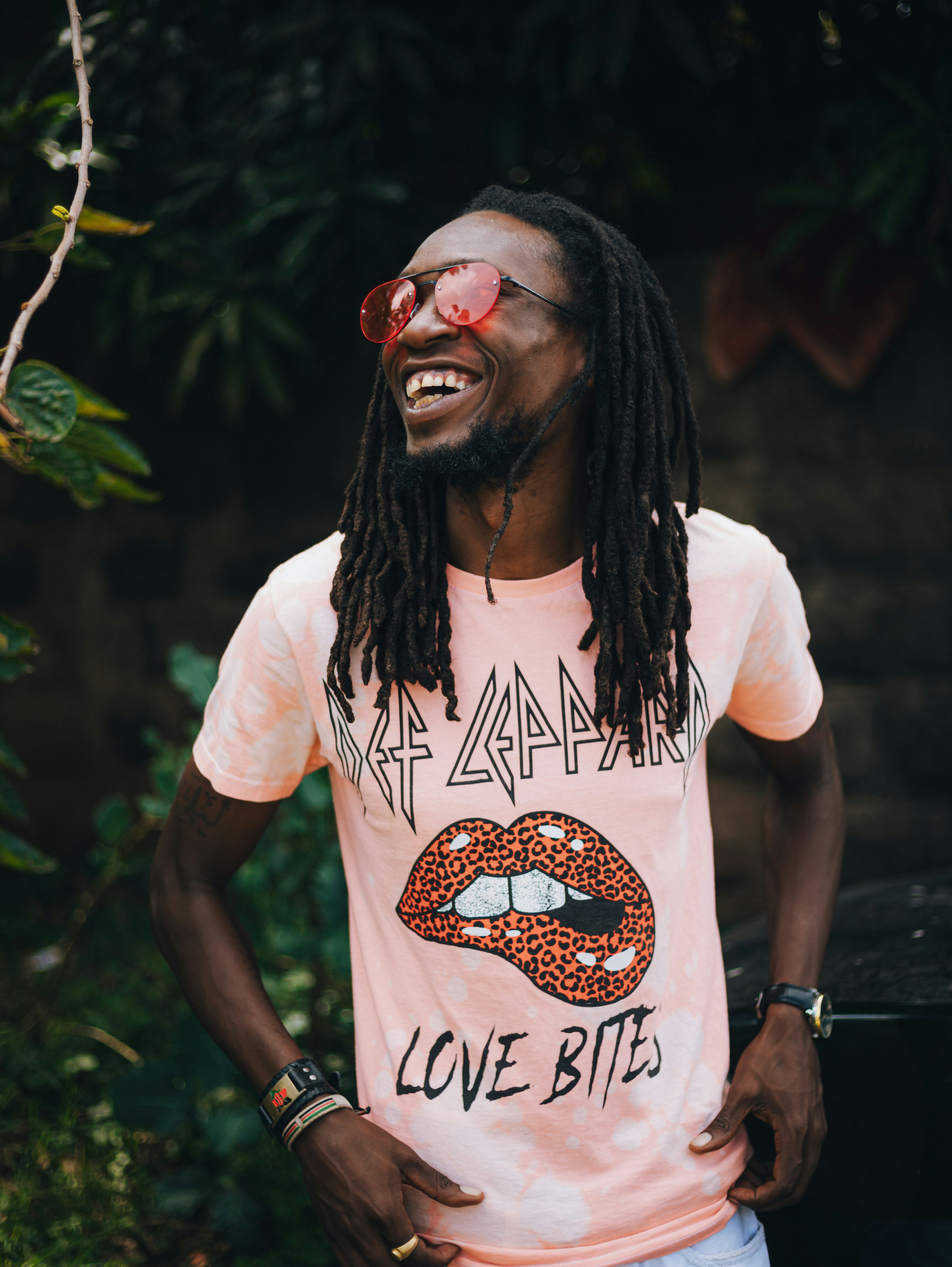 Homem com dreadlocks usando uma camiseta rosa e óculos escuros