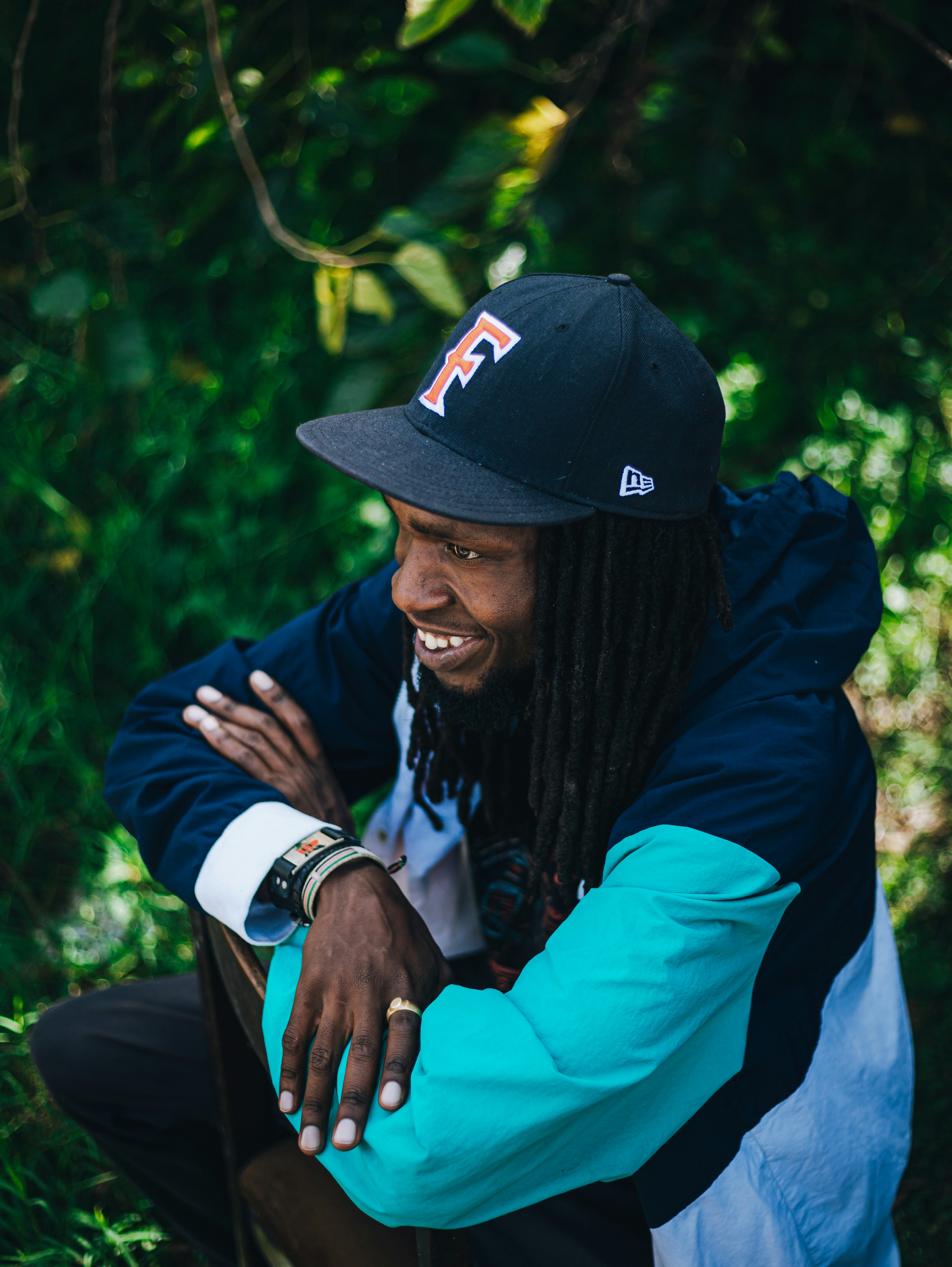 Hombre con rastas con gorra y chaqueta de béisbol.