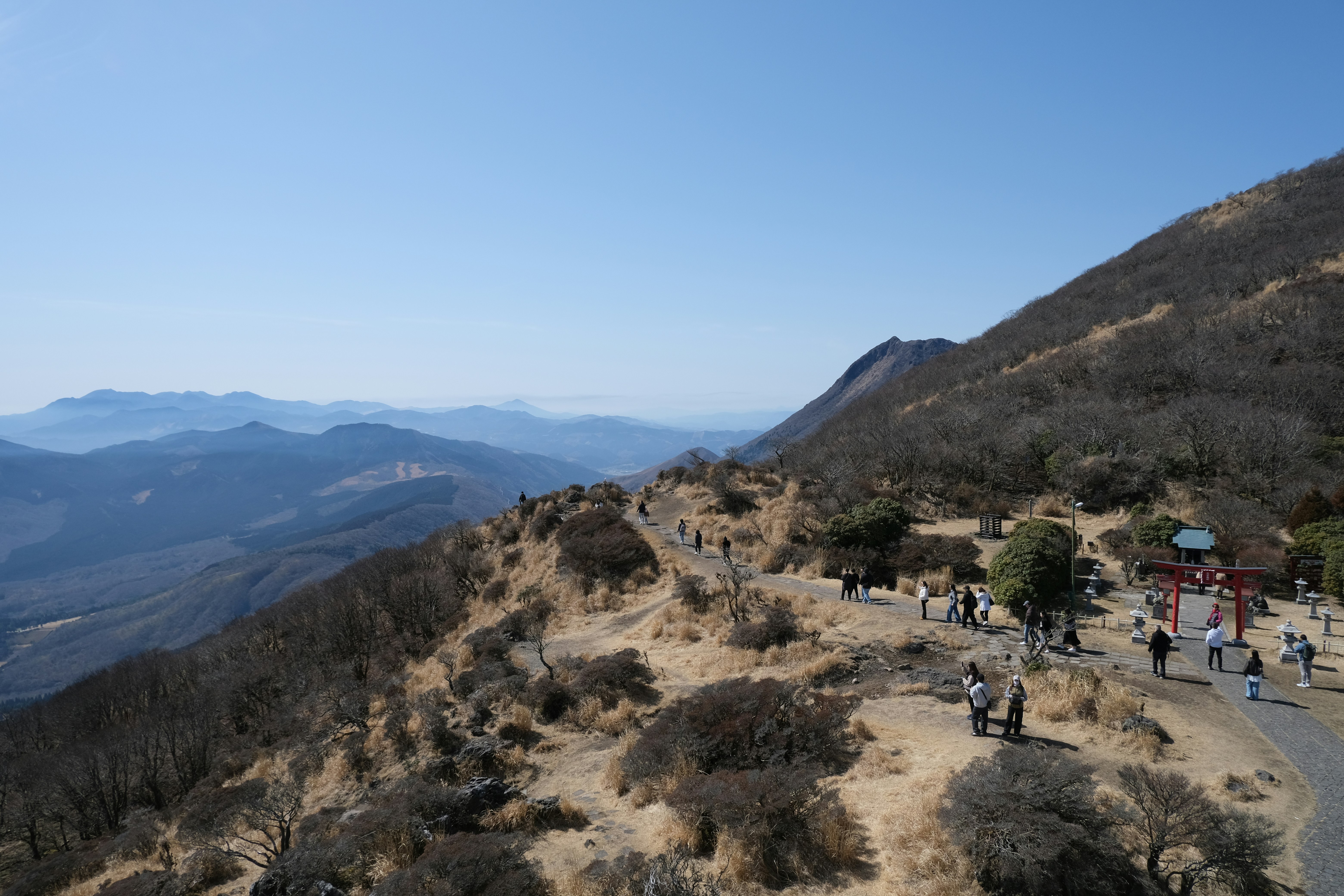 人々は遠くに青い山々が見える山脈の尾根を歩いています。