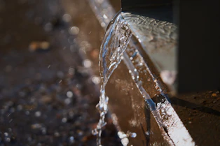 Water spraying from a pipe onto the ground.