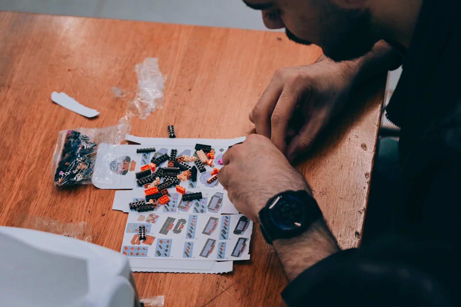 Adult assembling a detailed construction model from small pieces