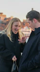 Couple in black coats with city skyline background