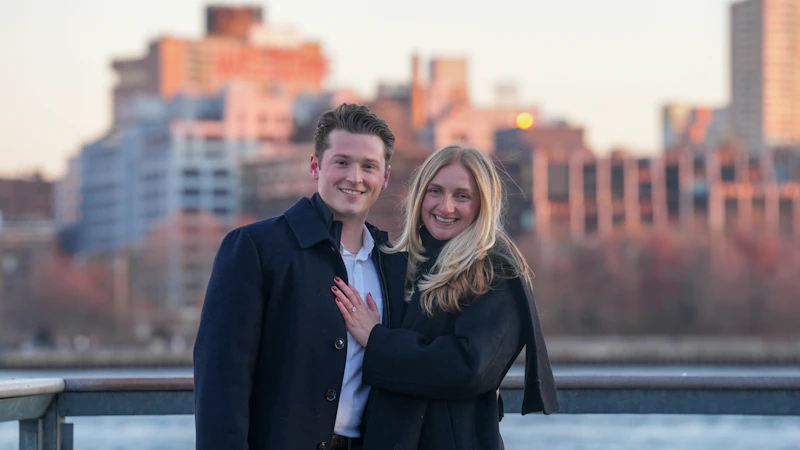 pareja sonriente con el skyline al atardecer